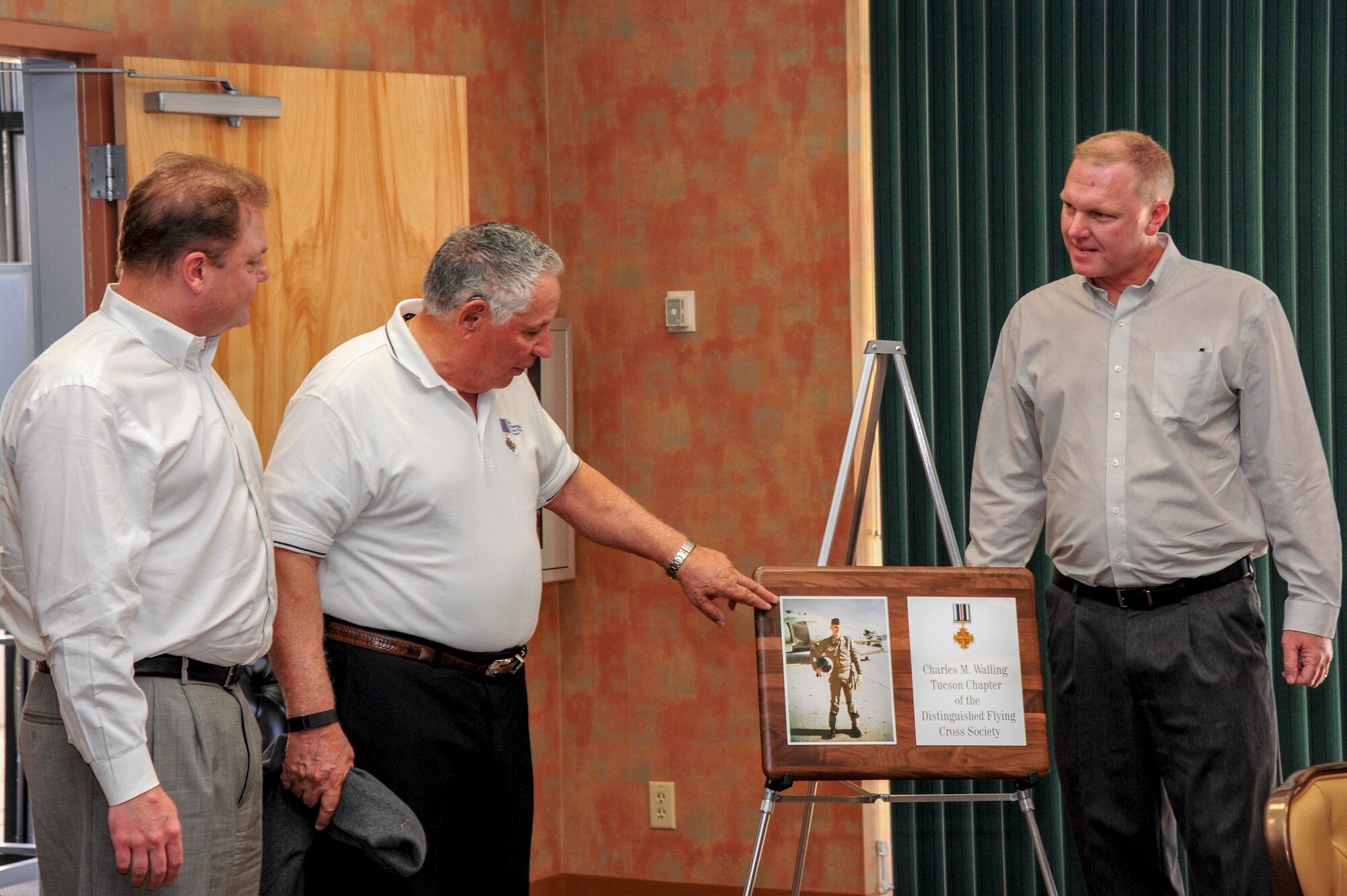 Mike Walling, left, and Jeff Walling, right, watch as Marty Lenzini, President of the Tucson Chapter of the Distinguished Flying Cross Society, unveils a plaque commemorating the renaming of the Tucson Chapter after their father, Charles M. Walling, at Davis-Monthan Air Force Base, Ariz., Jan. 13, 2016.  U.S. Air Force Lt. Col. Charles M. Walling died while flying an F4C Phantom that crashed during a close air support mission over Song Be Province, Vietnam, Aug. 8, 1996.  (U.S. Air Force Photo by Senior Airman Chris Massey/Released)