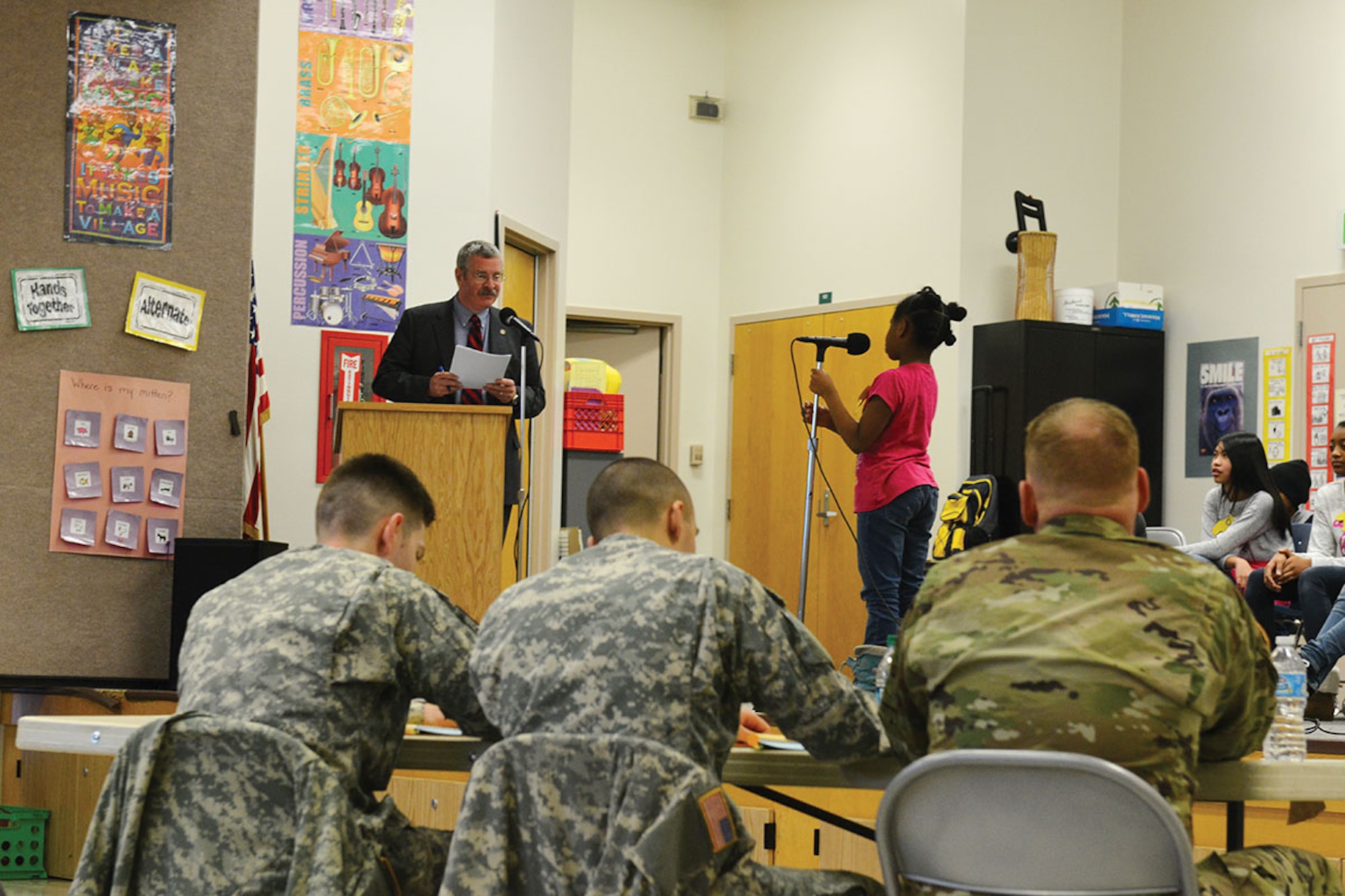 U.S. Army Sgt. Andrew Csog, a squad leader with the 17th Combat Sustainment Support Battalion (left), 2nd Lt. Kenneth Canali, a platoon leader with the 17th CSSB (center) and School partnership representative for the 17th CSSB, and Lt. Col. John Gavin, 17th CSSB commander listen to a student spell Arch as part of Ursa Major's spelling bee January 7 at the school. Volunteers from the 17th CSSB served as judges as part of the school partnership program Joint Base Elmendorf-Richardson has with 29 Anchorage School District locations. (U.S. Air Force photo by Airman 1st Class Kyle Johnson/Released)