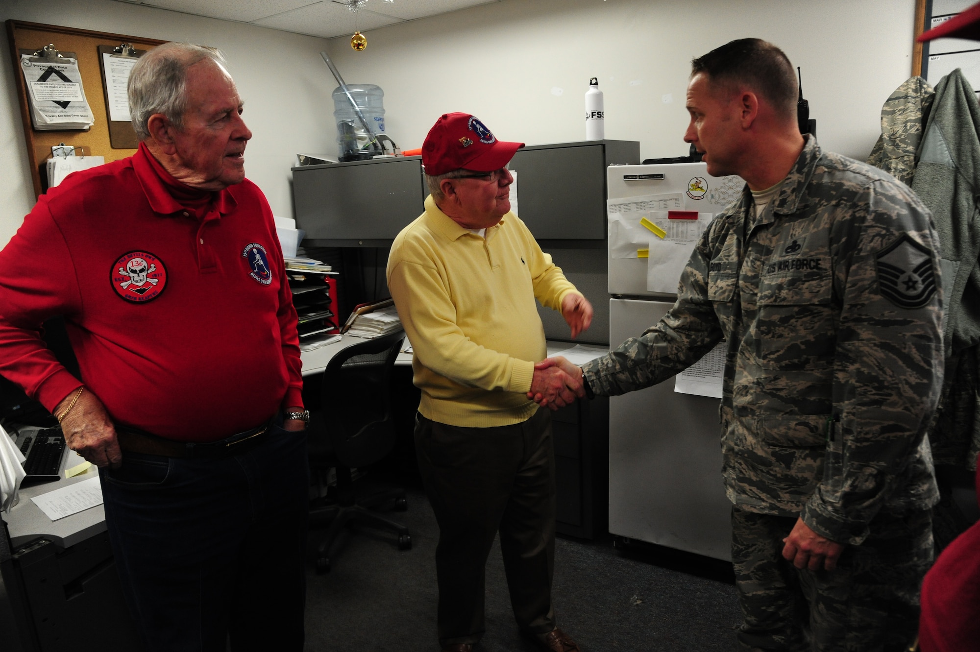 Bob Parks, the 13th Bomb Squadron Association (BS) vice president, middle, and Charlie Brown, the 13th BS Association president, left, shake hands with U.S. Air Force Master Sgt. Marty Boyd, the 13th Aircraft Maintenance Unit lead production superintendent, at Whiteman Air Force Base, Mo., Dec. 17, 2015. The veterans met with Airmen from different units, traded stories and educated Airmen from today’s 13th BS about the association. (U.S. Air Force photo by Senior Airman Keenan Berry)