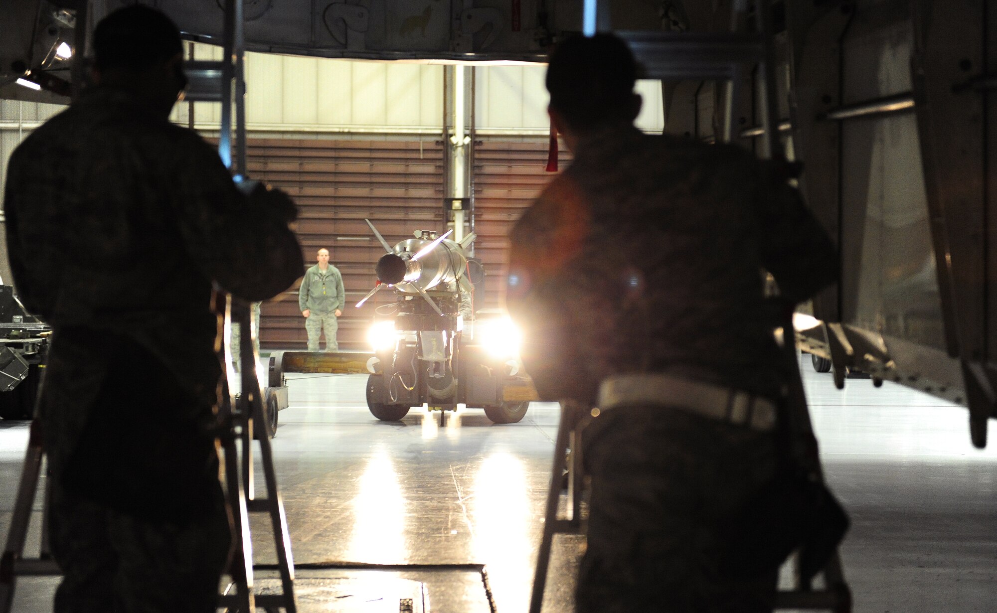 Load crew members from the 13th Aircraft Maintenance Unit wait as a GBU-28 B/B is transported on a jammer during a quarterly weapons load competition at Whiteman Air Force Base, Mo., Jan. 13, 2016. Each member of a weapons load crew has a set of specific tasks during loading operations. (U.S. Air Force photo by Senior Airman Joel Pfiester)