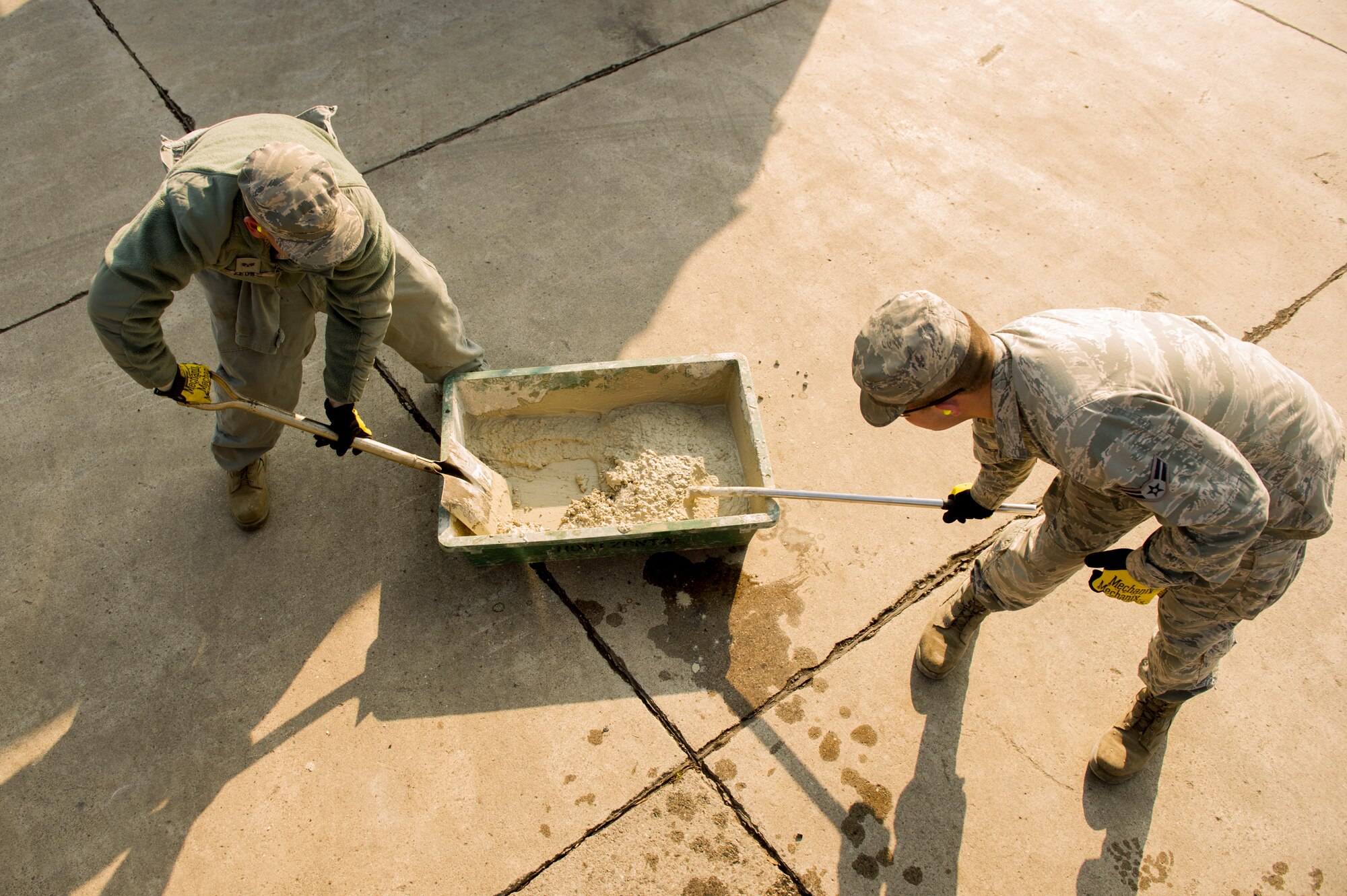 Senior Airman Tommy Zeus, left, and Airman 1st Class Brendan Kinser, 374th Civil Engineer Squadron pavements and heavy equipment technicians, prepare to perform a spot repair at Yokota Air Base, Japan, Jan. 13, 2016. As their job requires them to be experts with a wide assortment of machinery, the Airmen referred to as ‘Dirt Boys’ are able to assist other shops and squadrons around base. (U.S. Air Force photo by Airman 1st Class Delano Scott/Released)