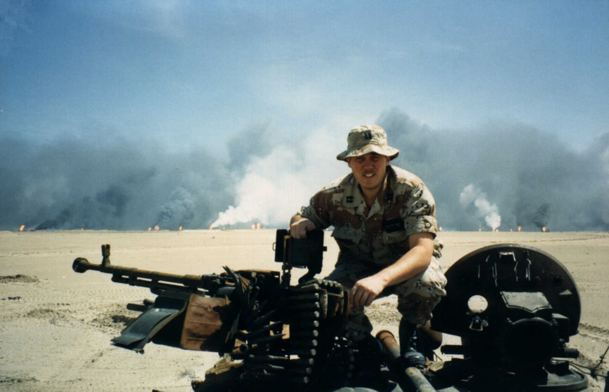 Wayland Patterson, AFCEC Readiness Directorate, sits atop a Russian tank in northern Kuwait in 1991 as oil wells set afire by a retreating Iraqi army burn.  Patterson deployed to Riyadh, Saudi Arabia, as a captain and chief of readiness for the engineering directorate in August 1990 as part of U.S. Central Command Air Force. (Courtesy photo)