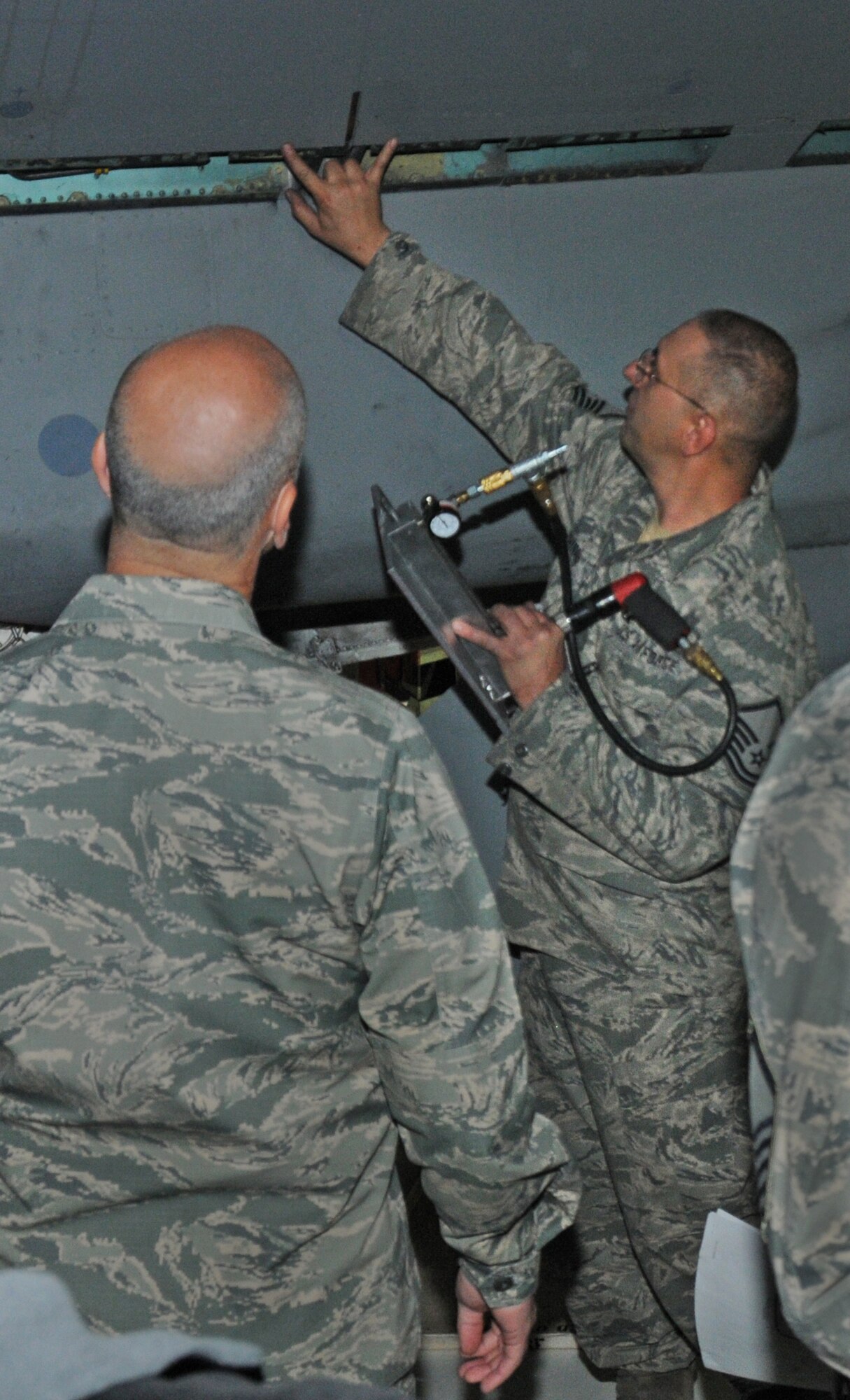 U.S. Air Force Master Sgt. Dave Chinander, 173rd Maintenance Group, demonstrates for Maj. Gent. T. Glenn Davis how a fixture is mounted directly to the wing and used to successively remove fine layers of titanium from the wing’s skin exposing the wing spar beneath. Through the opening maintainers can use various inspection techniques such as an eddy current tester to determine if the spar is sound, however without this small opening it is not possible to conduct any meaningful inspection. (U.S. Air National Guard photo by Master Sgt. Jennifer Shirar\released)