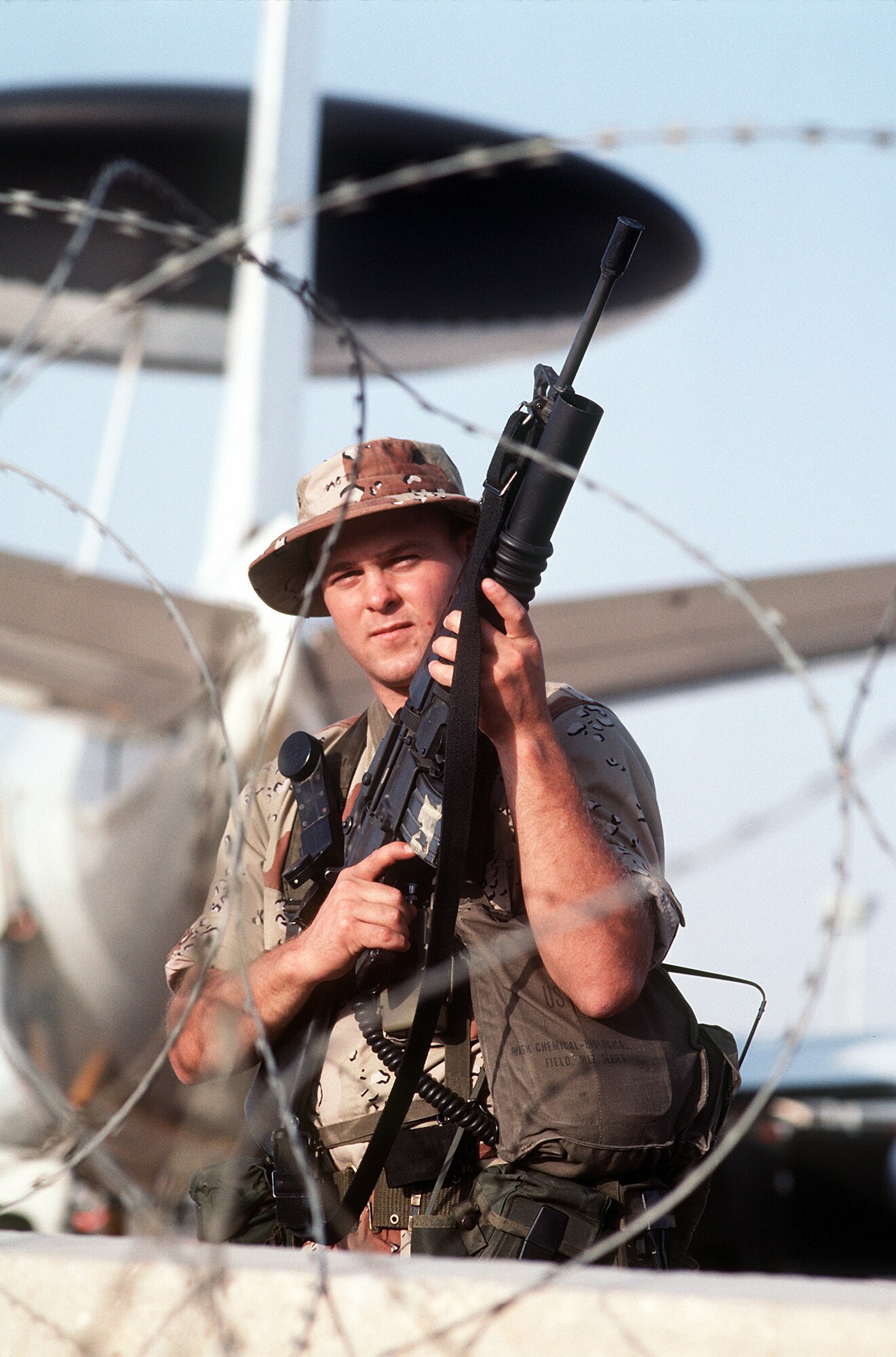 Airman 1st Class Robert Mott of the 90th Security Police Group stands guard near an E-3A Sentry aircraft during Operation Desert Shield, which led up to Desert Storm. Airman Mott is armed with an M-16A1 rifle equipped with an M-203 grenade launcher. The E-3 was the first aircraft deployed in the Desert Shield buildup. When combat activities began, nearly half of all E-3s were in the air as part of the round-the-clock coverage. (Air Force photo/Released)