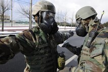 Senior Airmen Matthew McDonough and Nebil Ali, 8th Civil Engineer Squadron emergency management journeymen decontaminate each other before passing through the zone trasition point. Emergency management specialists at Kunsan Air Base develop plans to ensure Airmen here will keep the mission going. (U.S. Air Force photo by Senior Airman King/Released)