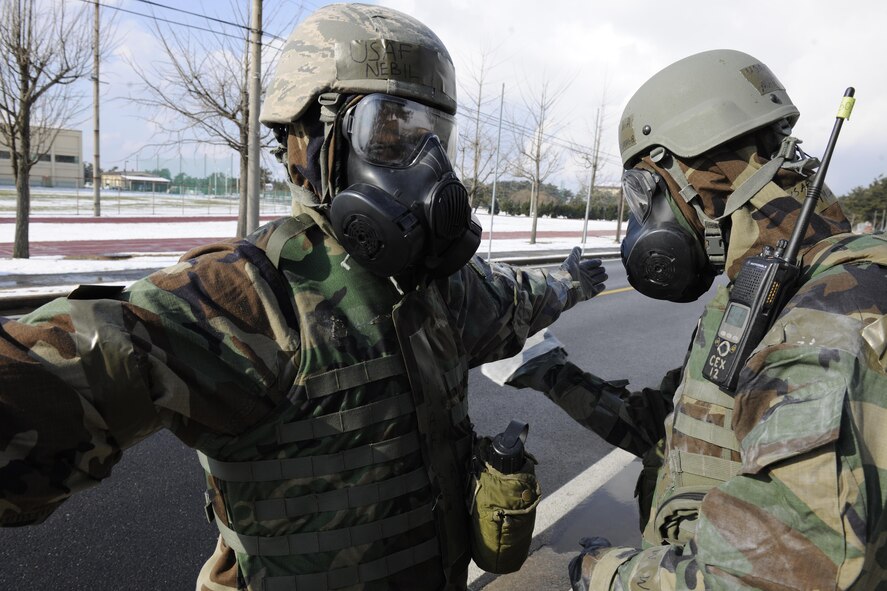 Senior Airmen Matthew McDonough and Nebil Ali, 8th Civil Engineer Squadron emergency management journeymen decontaminate each other before passing through the zone trasition point. Emergency management specialists at Kunsan Air Base develop plans to ensure Airmen here will keep the mission going. (U.S. Air Force photo by Senior Airman King/Released)