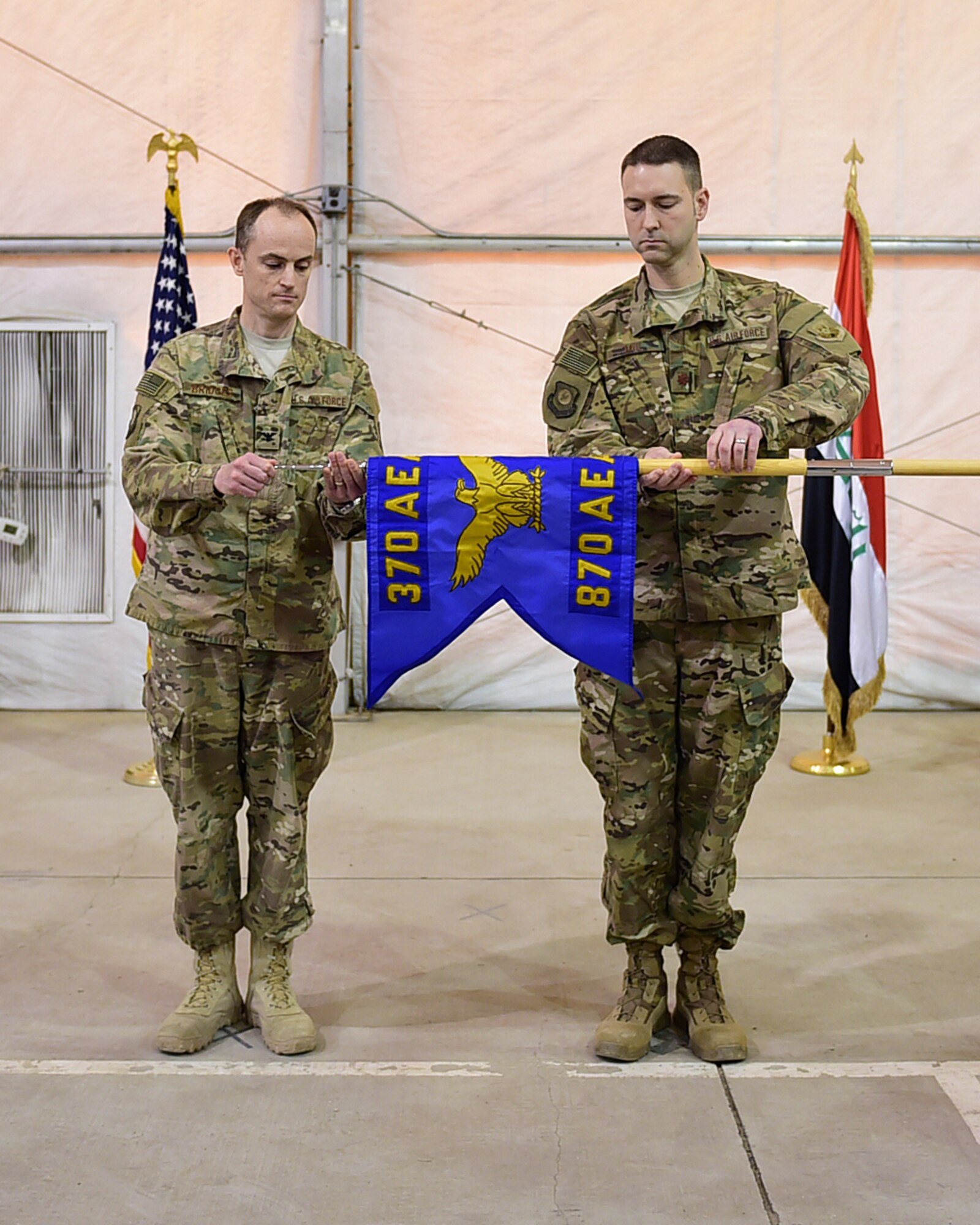 Col. Bradley Bridges, 370th Air Expeditionary Advisory Group commander, and Maj. Ross “Alex” Mol, 870th Air Expeditionary Advisory Squadron commander, unveil the 870th AEAS guidon during a unit activation ceremony Jan. 9, 2016 in Baghdad, Iraq. The 870th AEAS provides direct support to the Iraqi Air Force through logistics advise and assist missions, and commands all aerial ports in Iraq. (U.S. Air Force photo by Staff Sgt. Jerilyn Quintanilla)
