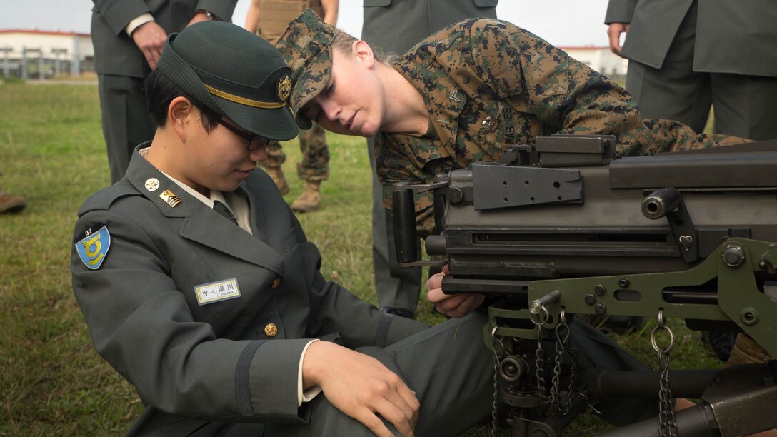 Cpl. Malynn Ochsner shows Japan Ground Self-Defense Force Officer Candidate Ayako Yukawa how to operate a MK19 machine gun, MOD 3 on Camp Kinser, Okinawa, Japan, Jan. 15. Three hundred and sixty JGSDF officer candidates visited Combat Logistics Regiment 35 to complete joint and combined operation requirements. The cadets watched Marine Corps Martial Art Program demonstrations, learned the capabilities of various machine guns the Marine Corps uses, and observed a static display of motor transportation vehicles. Ochsner, from Pflugerville, Texas, is a distribution management specialist with 3rd Supply Battalion, CLR-35, 3rd Marine Logistics Group, III Marine Expeditionary Force. 