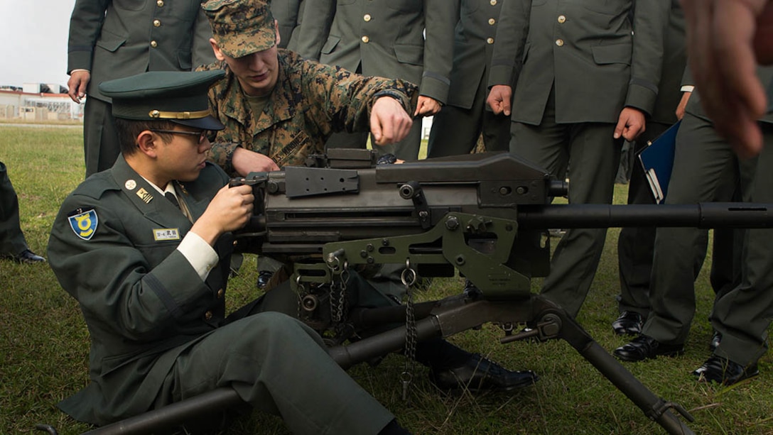 Pfc. Cooper Rottinghaus shows Japan Ground Self-Defense Force officer candidate Kazuhisa Takeda how to operate a MK19 machine gun, MOD 3 on Camp Kinser, Okinawa, Japan, Jan. 15. Three hundred and sixty JGSDF officer candidates visited Combat Logistics Regiment 35 to complete joint and combined operation requirements. Rottinghaus, from Stilwell, Kansas, is a maintenance management specialist with 3rd Supply Battalion, CLR-35, 3rd Marine Logistics Group, III Marine Expeditionary Force. 