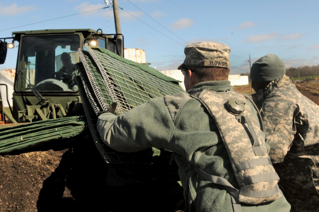 Army Spc. Alexander Flowers, foreground, helps unload barriers that will be used to build a levee to support Operation Winter River Flooding in Krotz Springs, La. Jan. 10, 2016 Flowers is assigned to the Louisiana Army National Guard’s 256th Infantry Brigade Combat Team. Louisiana National Guard photo by Army Staff Sgt. Greg Stevens