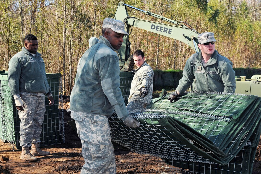 Army Spc. Alexander Flowers, right, helps a fellow soldier move barriers that will be used to build a levee to support Operation Winter River Flooding in Krotz Springs, La. Jan. 10, 2016. Flowers is assigned to the Louisiana Army National Guard’s 256th Infantry Brigade Combat Team. Louisiana National Guard photo by Army Staff Sgt. Greg Stevens