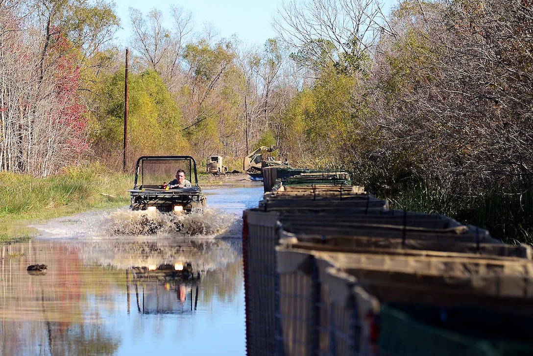 A soldier drives an all-terrain vehicle through high waters while checking on the progress of a levee construction project on Avoca Island, La., Jan. 11, 2016. Louisiana National Guard photo by Army Spc. Joshua Barnett