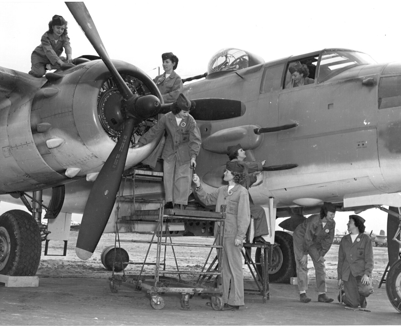 Women were once again needed in the Second World War.  Pictured here are women in just one of the many jobs they performed, they are putting the finishing touches on a PBJ medium bomber.  Atop the engine nacelles at left is Pfc Thelma O. Martin.  Working on the cowling below her is PFC Ruth T. Dincau, while Pfc Eunice L. Anderson works on the propeller.  Directing them from the ground is crew chief T/Sgt Selma “Rusty” Olson.  Adjusting machine gun covers is PFC Bettie L. Smith.  Sgt Margaret A. Engwald is in the cockpit and Pvt Carol C. Peters is crossing under the plane to the other side.  Working on the landing gear are PFC Eleanor D. Moore and Pvt Frances V. Gulbransen. 
DEFENSE DEPT PHOTO (MARINE CORPS) 8927