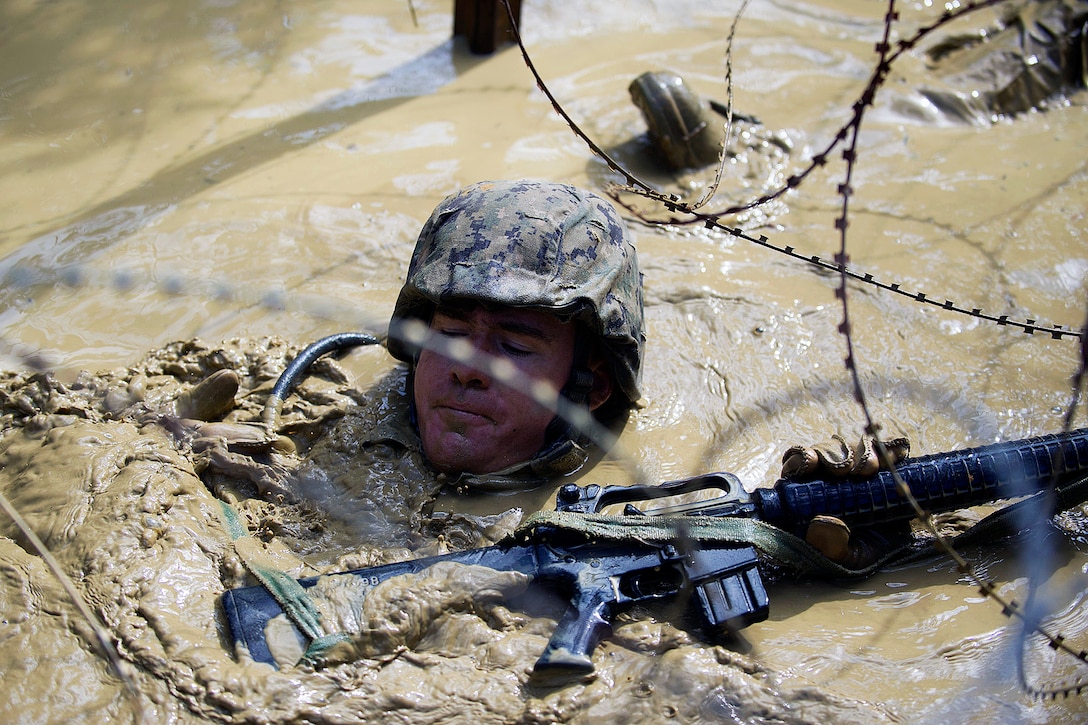 U.S. Navy Petty Officer 2nd Class Shawn P. Conley traverses a mud-filled trench during a jungle warfare training evolution in Okinawa, Japan, Jan. 12, 2016. Conley is assigned to Naval Mobile Construction Battalion 3. U.S. Navy photo by Petty Officer 1st Class Michael Gomez