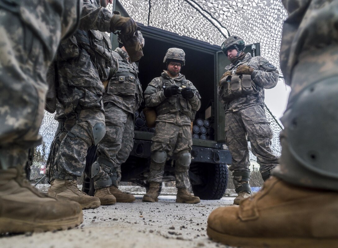 Army Pfc. Emilio Ojeda, center, talks to team members about the fuse for M119A2 105 mm howitzer rounds before a live-fire exercise on Joint Base Elmendorf-Richardson, Alaska, Jan. 11, 2016. Ojeda is assigned to the 25th Infantry Division’s 2nd Battalion, 377th Parachute Field Artillery Regiment, 4th Infantry Brigade Combat Team. U.S. Air Force photo by Justin Connaher