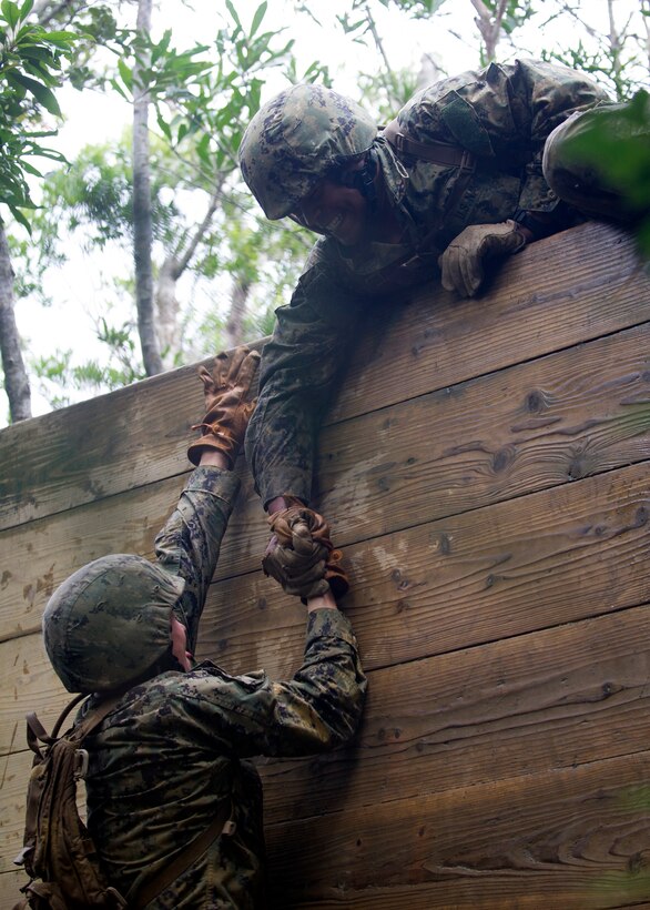 U.S. Navy Lt. j.g. Collin T. Sturdivant pulls a teammate up to reach the top of a wall obstacle during a six-hour endurance course at the Marine Corps Jungle Warfare Training Center in Okinawa, Japan, Jan. 12, 2016. Sturdivant is assigned to Naval Mobile Construction Battalion 3. U.S. Navy photo by Petty Officer 1st Class Michael Gomez