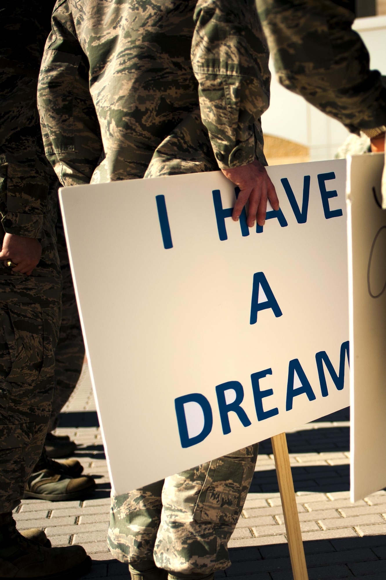 A U.S. Air Force Airman holds a sign at his side before the March on Goodfellow event at the Norma Brown building on Goodfellow Air Force Base, Texas, Jan. 15, 2016. The event commemorated the marches Martin Luther King Jr. and his supporters led during the civil rights movement. (U.S. Air Force photo by Senior Airman Scott Jackson/Released)