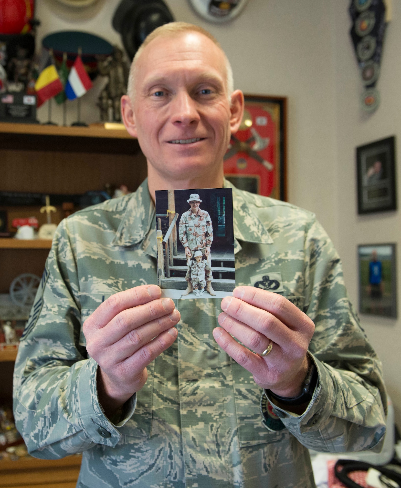Chief Master Sgt. Richard Lien, 366th Civil Engineer Squadron fire department chief, holds a Desert Storm-era photo of himself with his oldest son, Jan. 13, 2016, at Mountain Home Air Force Base, Idaho. “I didn’t come home for a parade,” Lien said. “This is my victory parade, being with my oldest son.” (U.S. Air Force Photo by Airman Chester Mientkiewicz/RELEASED)