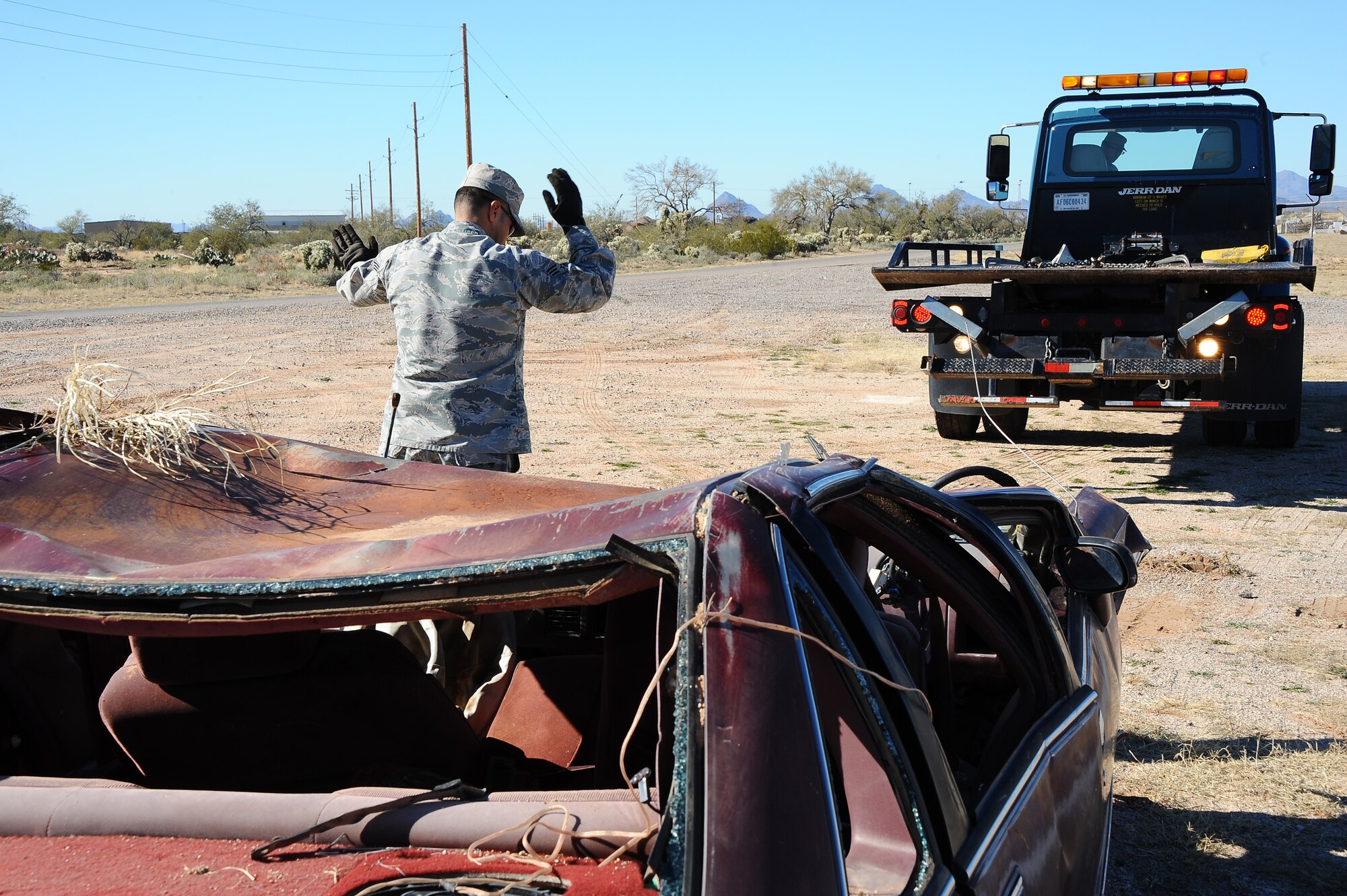 U.S. Air Force Senior Airman San Juan Valentin, 355th Logistics Readiness Squadron vehicle operator, spots an airman to align the bed of the rollback wrecker to the crashed vehicle during Cactus Flag: a large force employment exercise at Davis-Monthan Air Force Base, Ariz., Jan. 12, 2016. This exercise provided unit commanders with the flexibility to develop independent scenarios, and evaluate tailored objectives, that best reflect the mission and skills of their unit. (U.S. Air Force photo by Airman 1st Class Mya M. Crosby/Released)