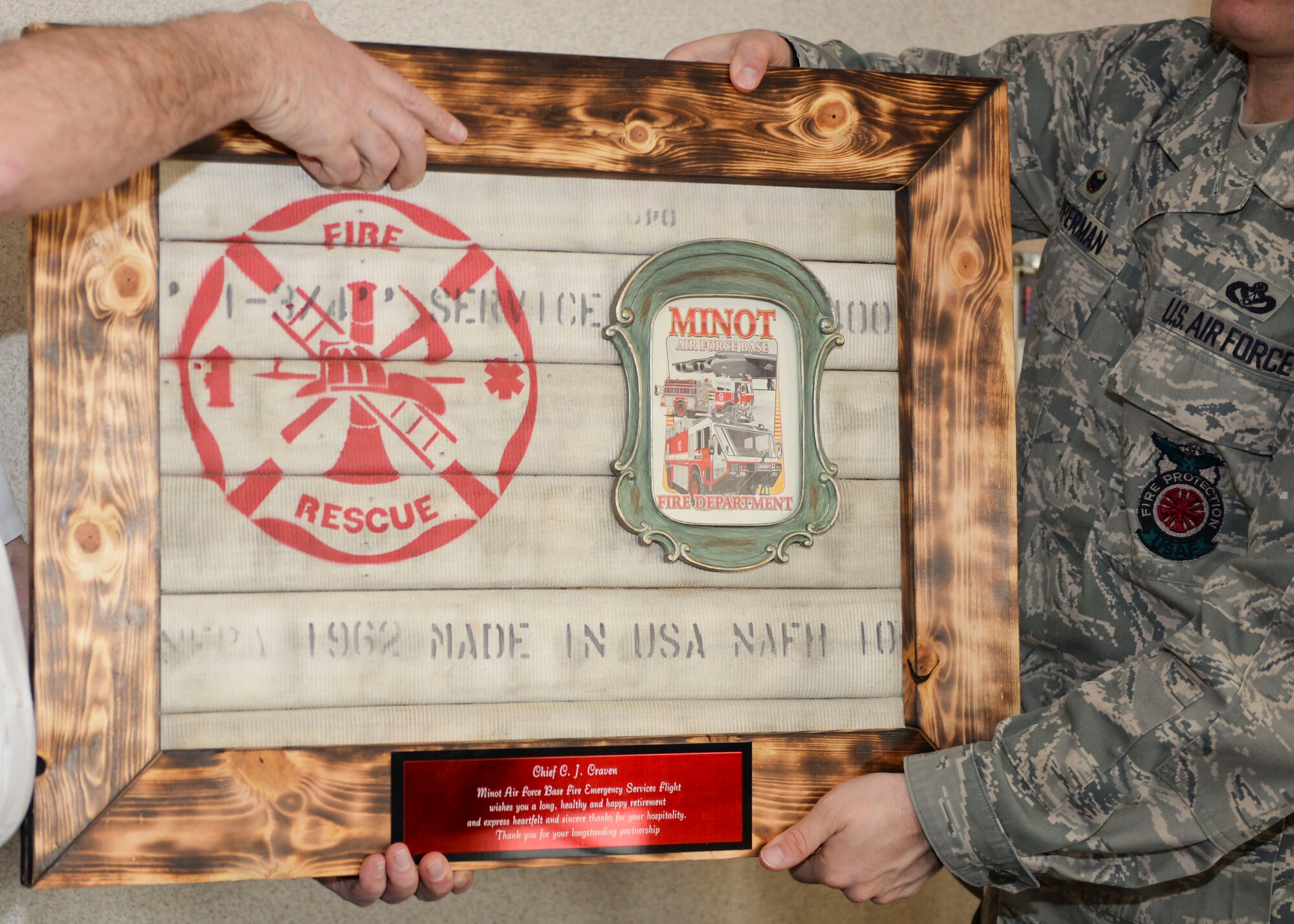 C.J. Cavern, former Minot city fire chief, is handed a going-away gift from Lt. Col. Bryan Opperman, 5th Civil Engineer Squadron commander, at Minot Air Force Base, N.D., Jan. 5, 2016.  According to Eidenschink, in order to effectively operate in today’s environment, fire chiefs must be able to rely on established partnerships to ensure we have the necessary manpower and equipment when needed to safely mitigate emergencies. (U.S. Air Force photo/Airman 1st Class J.T. Armstrong)