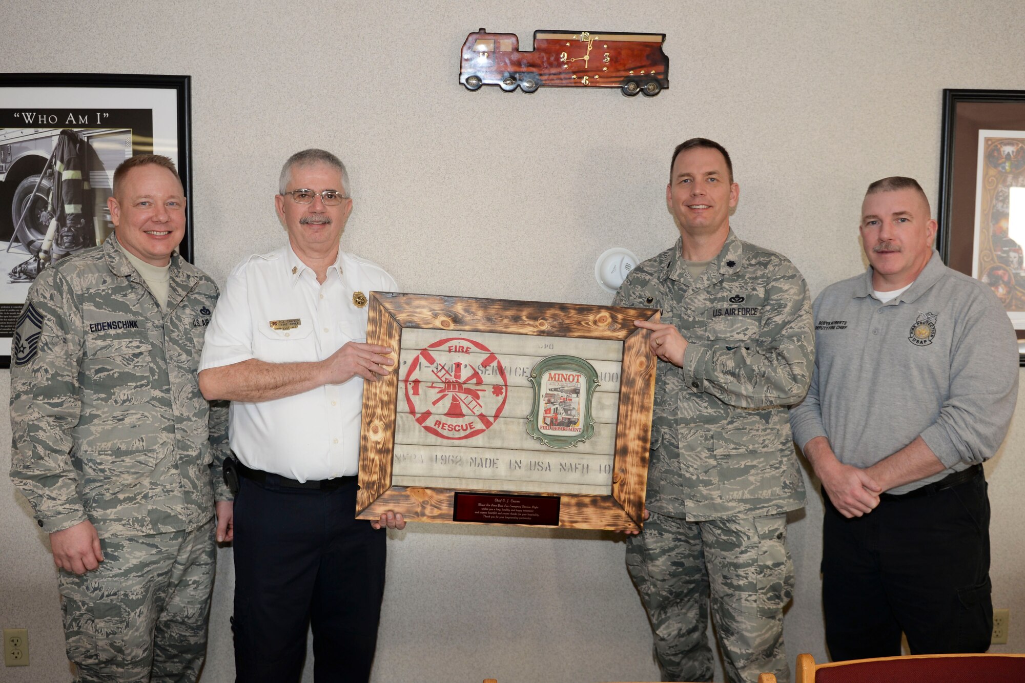 Chief Master Sgt. Eidenschink, 5th Civil Engineer Squadron fire chief (left), C.J. Cavern, former Minot city fire chief, Lt. Col. Bryan Opperman, 5th CES commander and Robyn Roberts, 5th CES deputy fire chief, pose with a going-away gift at Minot Air Force Base, N.D., Jan. 5, 2016. According to Eidenschink, in order to effectively operate in today’s environment, fire chiefs must be able to rely on established partnerships to ensure we have the necessary manpower and equipment when needed to safely mitigate emergencies. (U.S. Air Force photo/Airman 1st Class J.T. Armstrong)