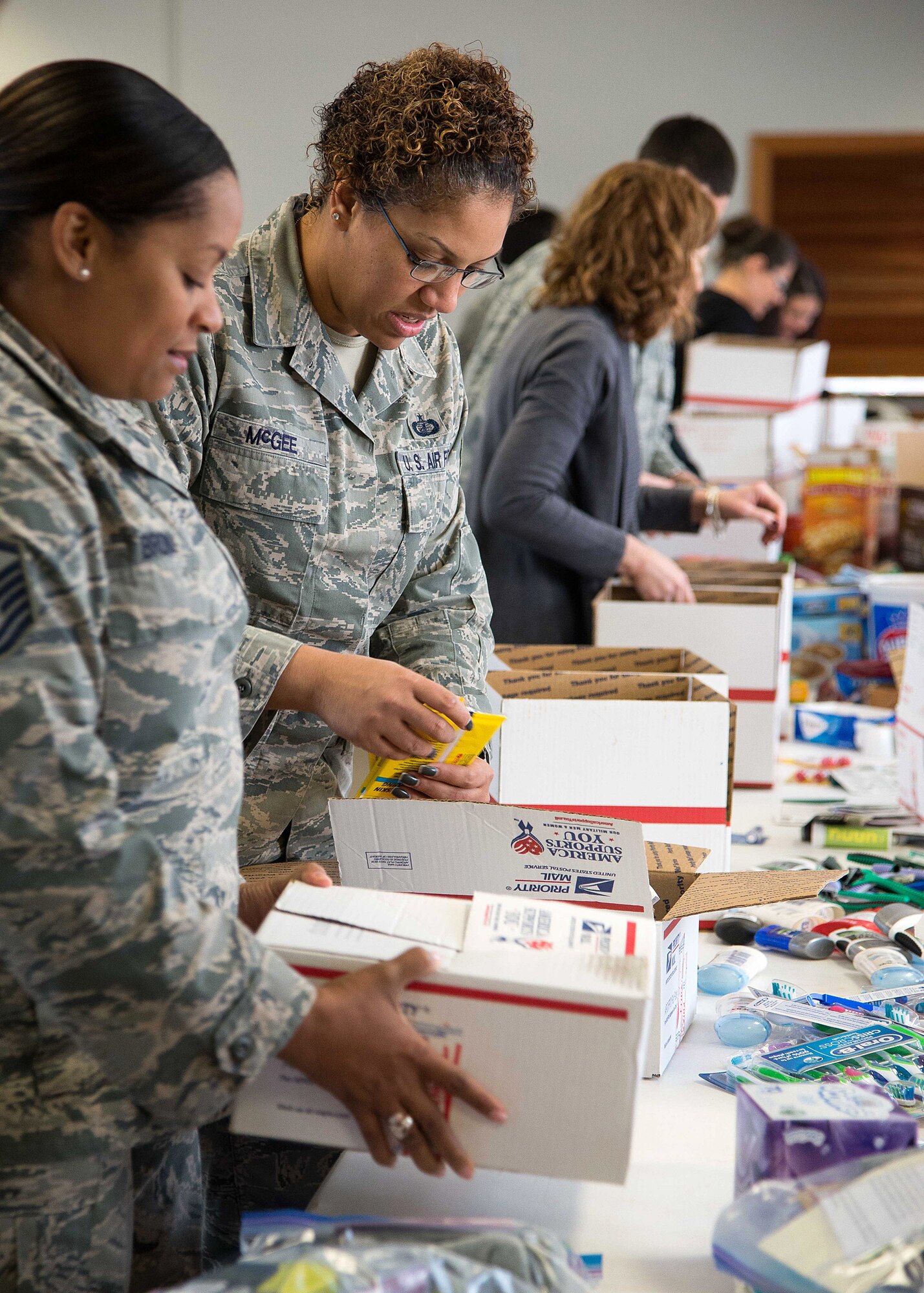 Master Sgt. Katrina Brown, left, and Tech. Sgt. Chrystle McGee, center, along with others, fill boxes of donated items during the Company Grade Officer Troop Care Drive at the base chapel Jan. 14. More than 45 volunteers assembled more than 200 packages that will be mailed to deployed personnel serving overseas. (U.S. Air Force photo by Mark Herlihy)