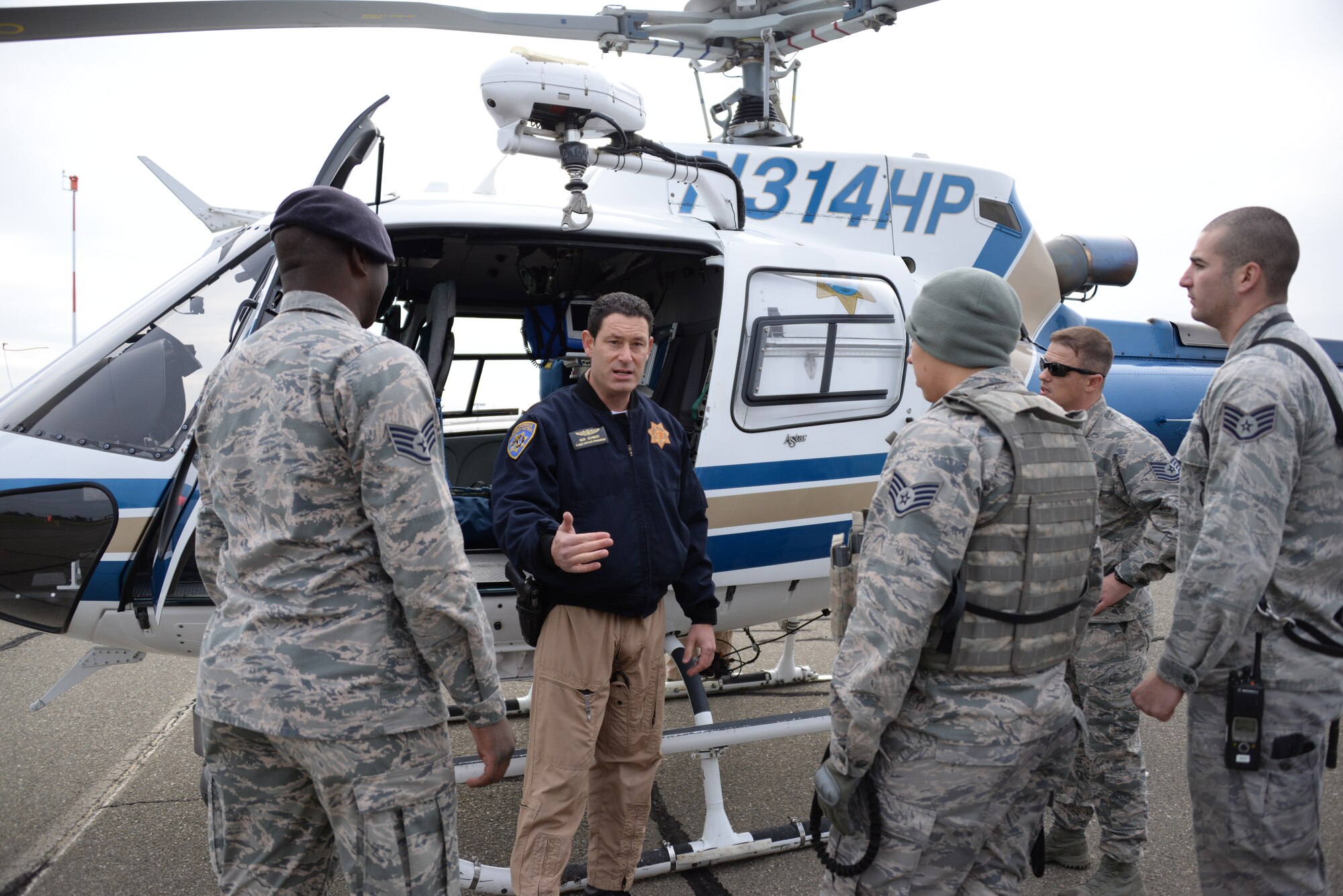 Military working dog handlers from the 60th SFS are briefed Jan. 11 at Travis Air Force Base, California. Mike McAuley, CHP helicopter pilot, explains how to safely enter and exit the helicopter.. (U.S. Air Force photo by Airman 1st Class Amber Carter)
