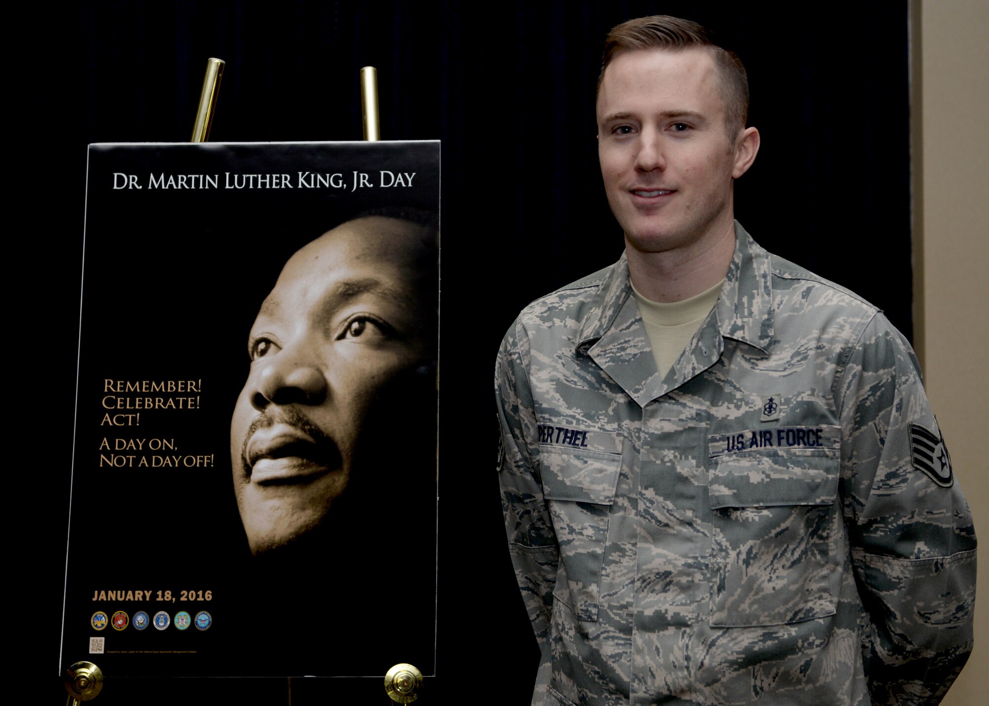 Staff Sgt. Erik Perthel, 28th Medical Operations Squadron public health technician, stands in front of the Martin Luther King, Jr. Day of Observance poster at Ellsworth Air Force Base, S.D., Jan. 12, 2016. Perthel spoke on the importance of MLK Jr. Day of Observance and diversity during a recognition event. (U.S. Air Force photo by Airman Sadie Colbert/Released)