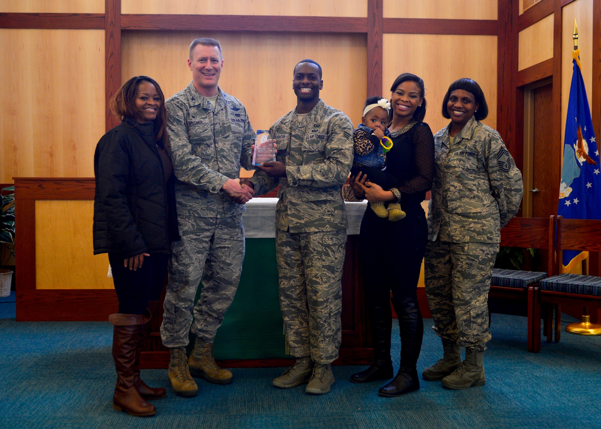 Col. Michael Grismer, 436th Airlift Wing commander, presents Senior Airman Omari Slaughter, 436th AW Command Post controller, an award at the Dr. Martin Luther King, Jr. Commemorative Ceremony Jan. 14, 2016, at Chapel 1 on Dover Air Force Base, Del. Slaughter was one of four individuals who won an award for sketching an image of Dr. King. (U.S. Air Force photo/Senior Airman William Johnson)