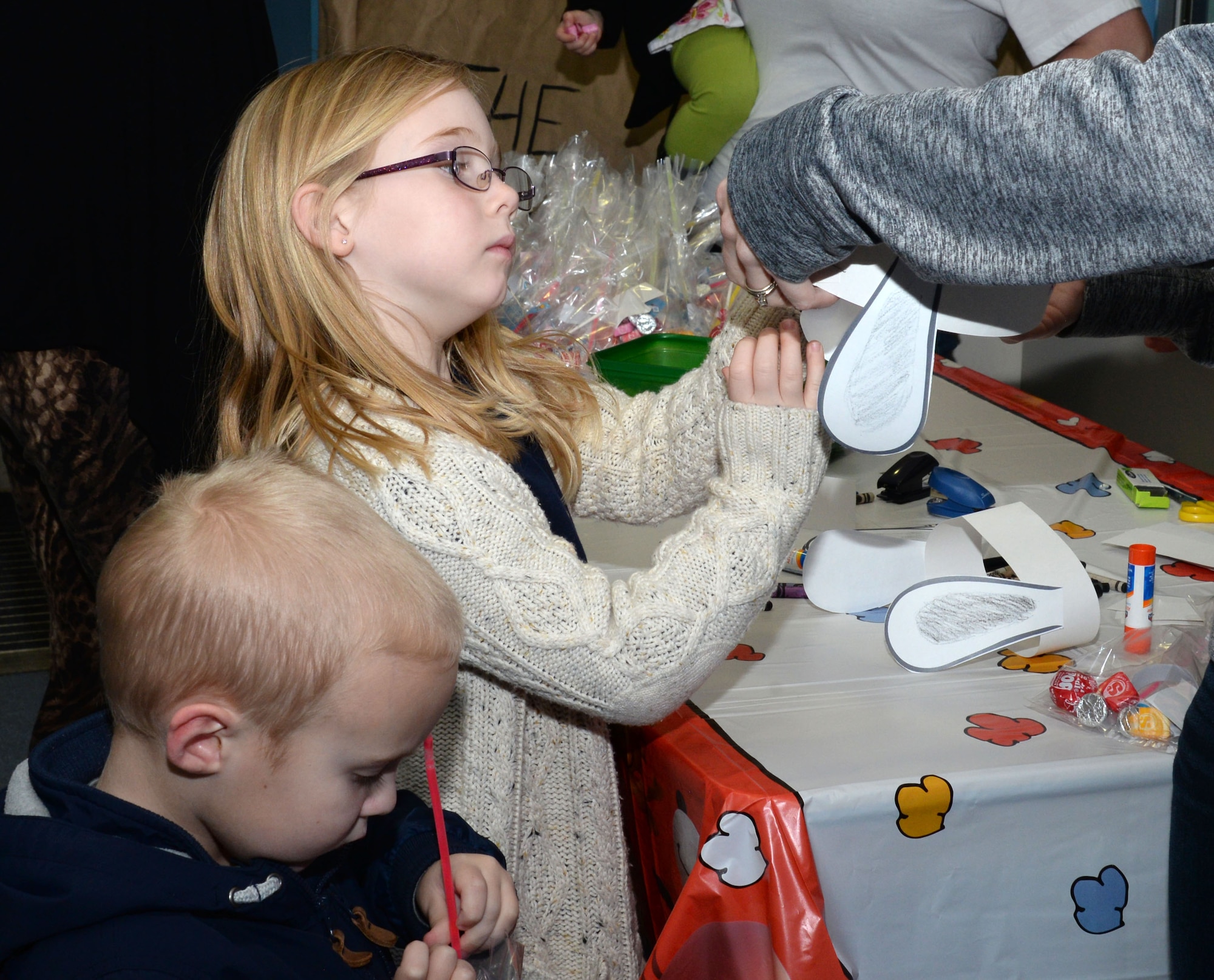 Children make Snoopy ears before watching The Peanuts Movie during a Hearts Apart event for families of deployed Airmen Jan. 14, 2016, at the base theater on RAF Mildenhall, England. Team Mildenhall Spouses Club provided snacks, goodie bags and a craft table to encourage a kid-friendly theater environment. The evening’s events were to help bring families closer together and develop a sense of community while their loved ones are deployed.  (U.S. Air Force photo by Airman 1st Class Justine Rho/Released)