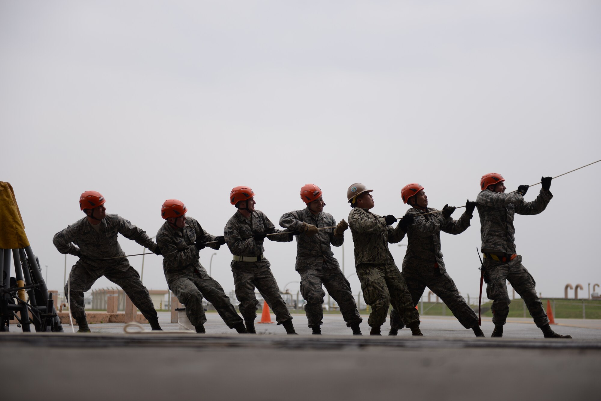U.S. Air Force Airmen of the 18th Aircraft Maintenance Squadron and a U.S. Navy Seabee construction man of Naval Mobile Construction Battalion 3 pull on a tag line rope to stabilize a fin fold procedure Jan. 14, 2016, at Kadena Air Base, Japan. The top tail section of a KC-135 Stratotanker required removal for a rudder repair project. (U.S. Air Force photo by Senior Airman Peter Reft)