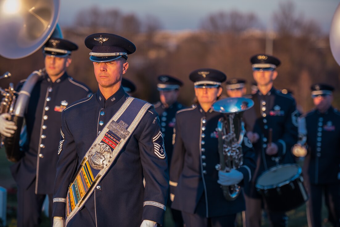 Picture of drum major Senior Master Sgt. Dan Valadie leading the Ceremonial Band at a funeral at Arlington National Cemetery. Clicking the picture leads to a link on the website defense.gov.