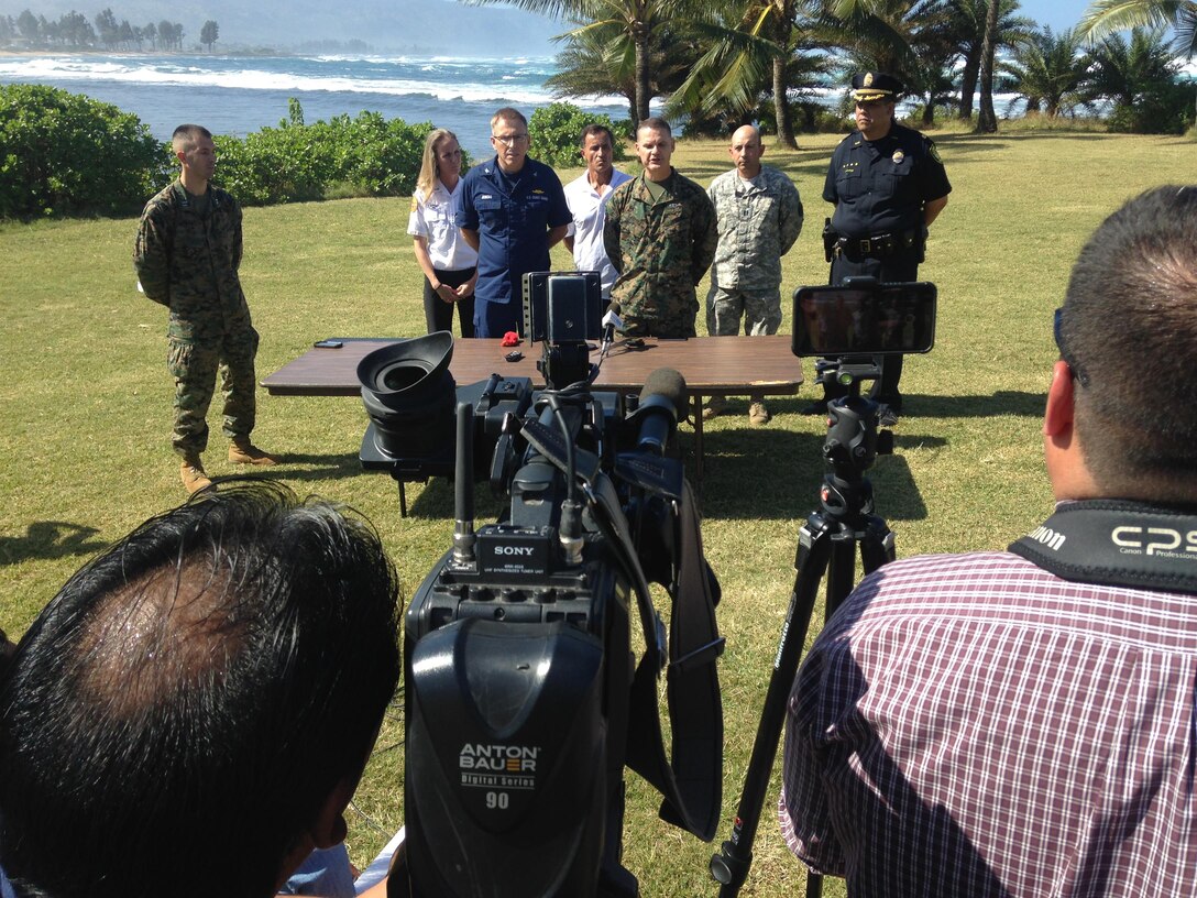 Marine Brig. Gen. Russell Sanborn, commanding general of the 1st Marine Aircraft Wing, and Coast Guard Capt. Jim Jenkins, chief of staff for the Coast Guard 14th District, conduct a press conference with other responders from Haleiwa Beach Park at the forward Incident Command Post Jan. 17, 2016. The press conference was held to provide an update on search efforts for the 12 missing Marine aviators. (U.S. Coast Guard photo by Lt. Scott Carr/Released)