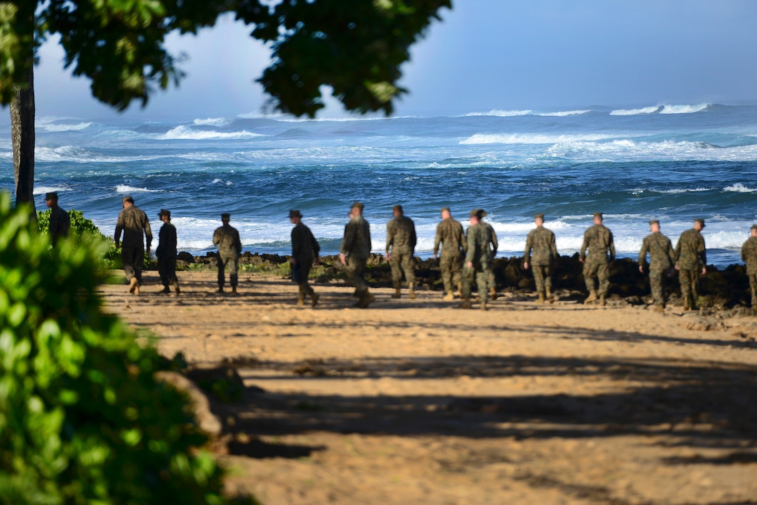 Marines walk the beach outside the Haleiwa Incident Command Post in Haleiwa, Hawaii, Jan. 18, 2016, during search efforts for 12 missing Marine pilots. U.S. Coast Guard photo by Petty Officer 1st Class Levi Read