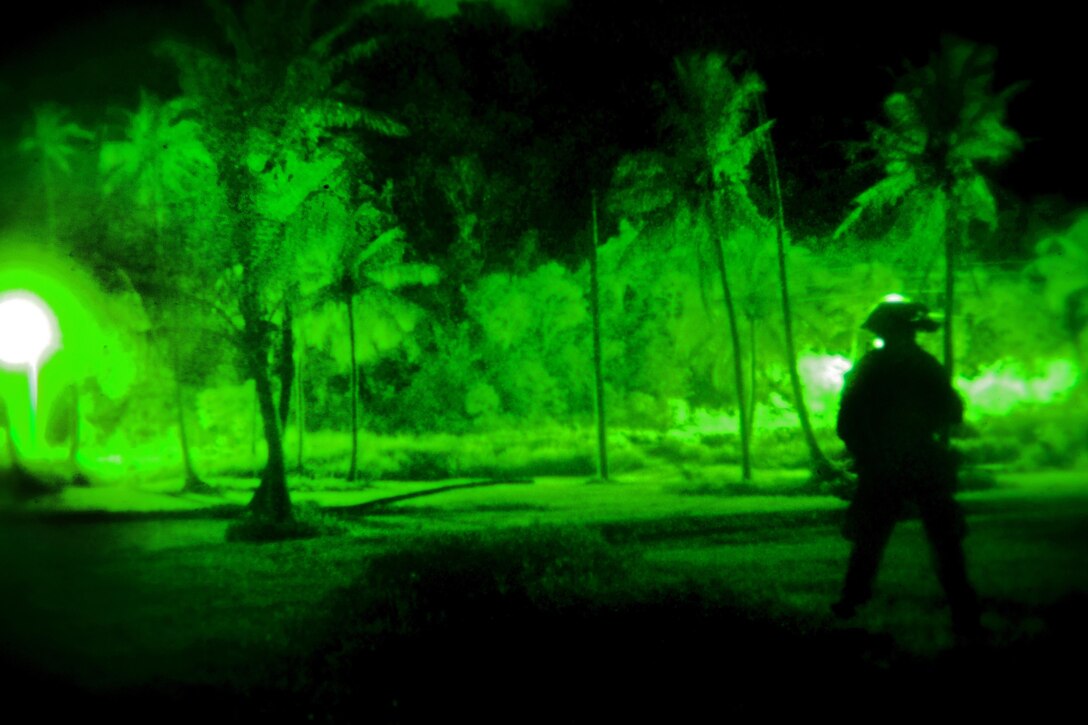 As seen through a night-vision device, Marine Corps Sgt. Eric Ortega provides security while waiting for a helicopter to land during an urban training exercise on Guam, Jan. 13, 2016. Ortega is an assistant communications chief assigned to Maritime Raid Force, 31st Marine Expeditionary Unit. U.S. Marine Corps Photo by Cpl. Thor J. Larson