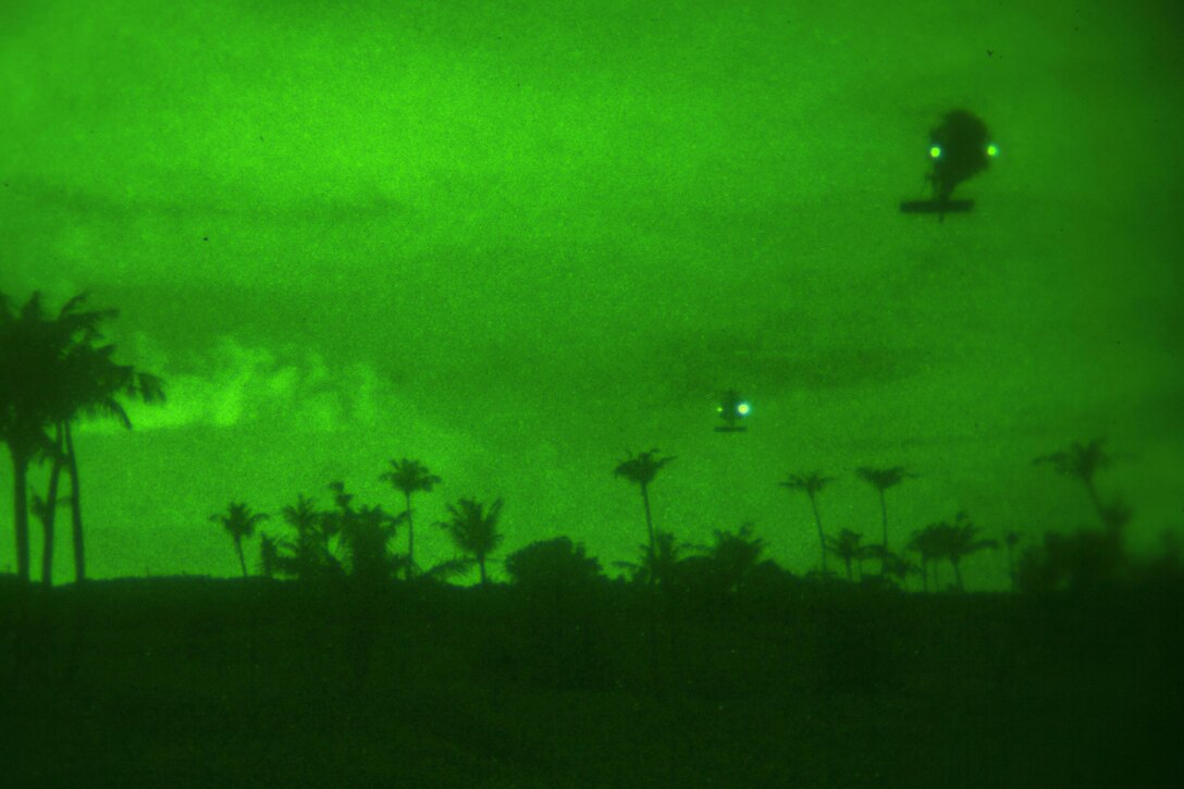 As seen through a night-vision device, two UH-60 Black Hawk helicopters fly two Marine teams to their objective during an urban training exercise on Guam, Jan. 13, 2016. The Marines are assigned to Maritime Raid Force, 31st Marine Expeditionary Unit. The raid is one scenario during the exercise to provide high-intensity, close-quarter battle training in an urban environment. U.S. Marine Corps Photo by Cpl. Thor J. Larson