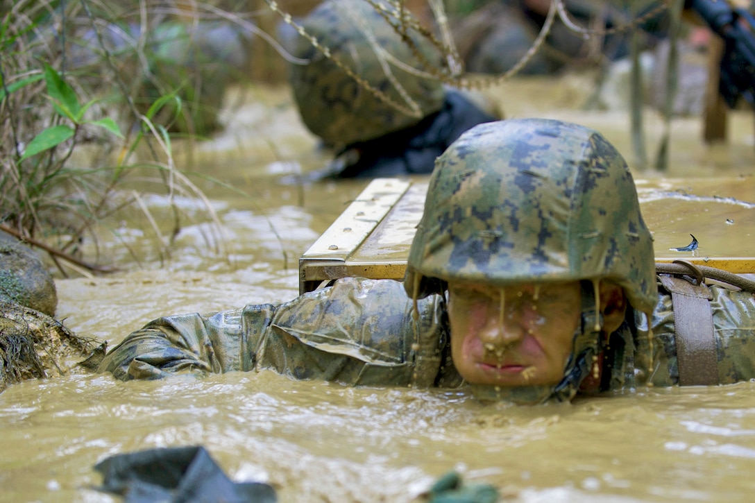 U.S. Navy Ensign Frank S. Sysko holds his breath while exiting a mud-filled trench during jungle warfare training evolution hosted by Marines with the Jungle Warfare Training Center in Okinawa, Japan, Jan. 12, 2016. Sysko is assigned to Naval Mobile Construction Battalion 3, which is deployed to several countries in the Pacific to perform construction operations and humanitarian assistance projects. U.S. Navy photo by Petty Officer 1st Class Michael Gomez 