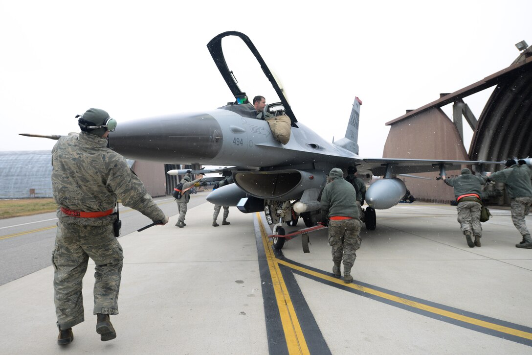 A team of 36th Aircraft Maintenance Unit crew chiefs move an F-16 Fighting Falcon into a hardened aircraft hangar on Osan Air Base, Republic of Korea, Jan. 12, 2016. The 36th AMU trains, equips and executes mission capabilities to ensure the 51st Fighter Wing is able to provide safety and deterrence to the ROK. (U.S. Air Force photo by Airman 1st Class Dillian Bamman/Released)