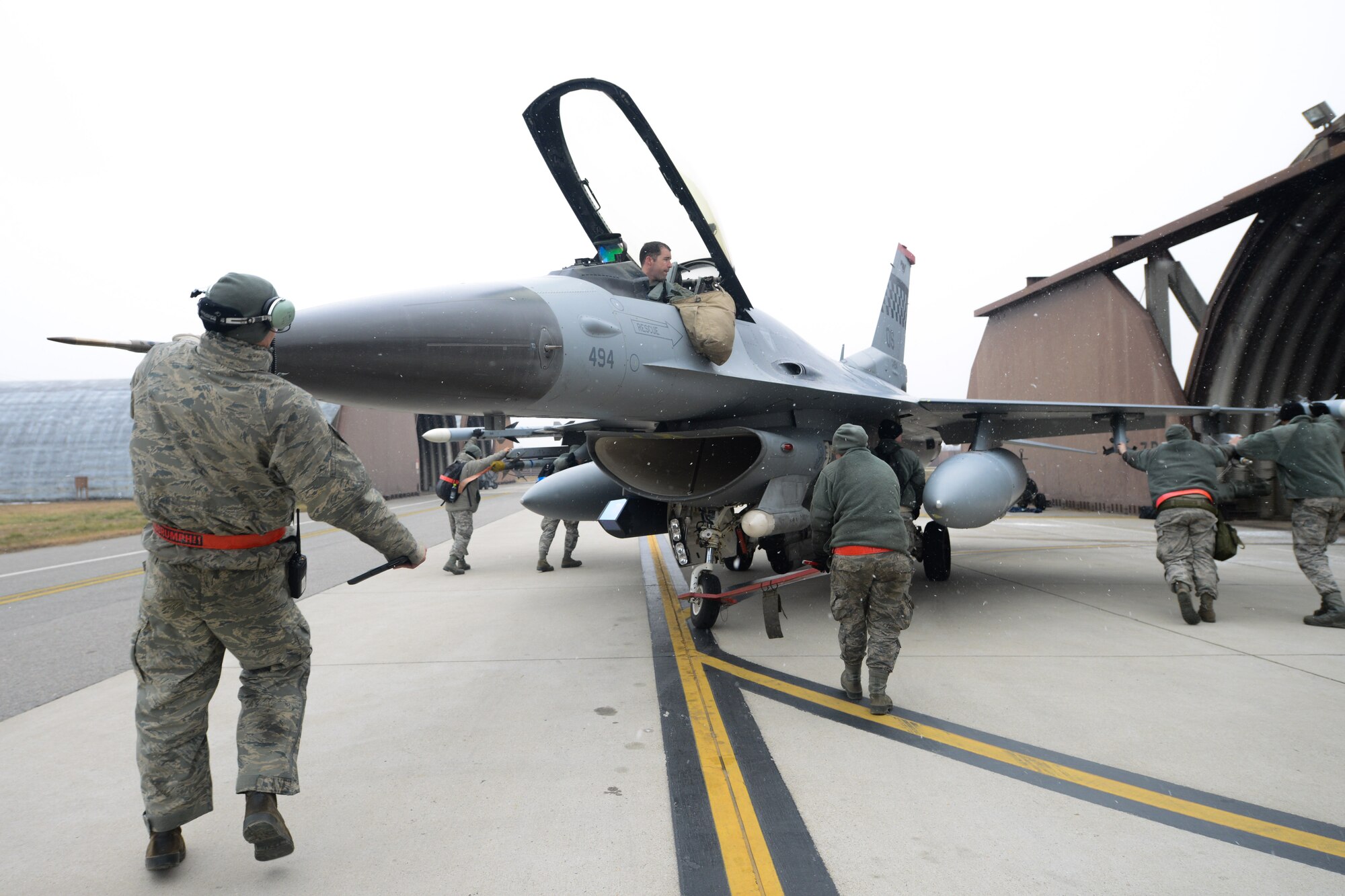 A team of 36th Aircraft Maintenance Unit crew chiefs move an F-16 Fighting Falcon into a hardened aircraft hangar on Osan Air Base, Republic of Korea, Jan. 12, 2016. The 36th AMU trains, equips and executes mission capabilities to ensure the 51st Fighter Wing is able to provide safety and deterrence to the ROK. (U.S. Air Force photo by Airman 1st Class Dillian Bamman/Released)
