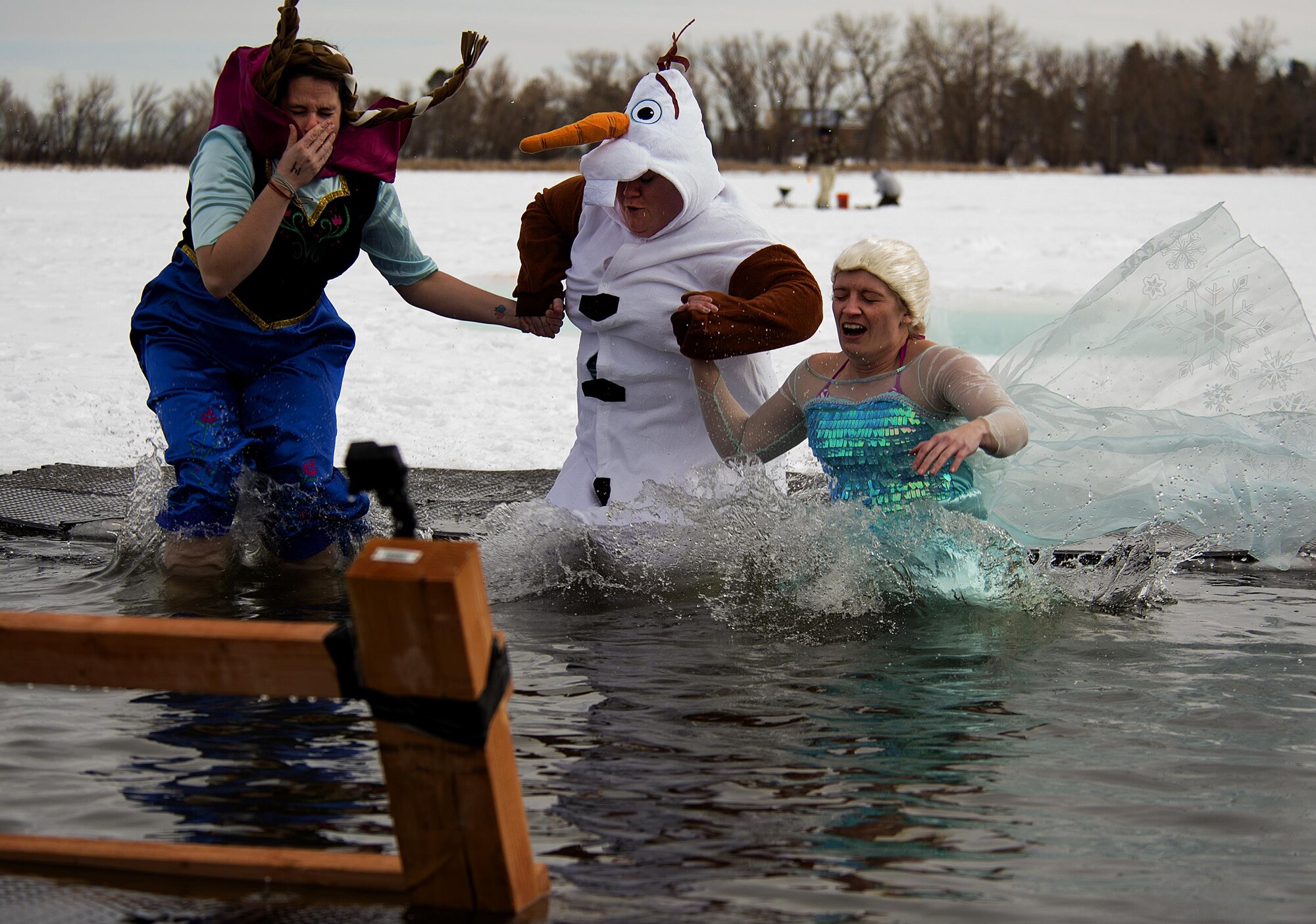 Katie Emmons, Erica Cushmore and Jenny Hall appropriately make the leap in the frozen Sloan Lake in Cheyenne, Wyo., wearing costumes from the movie “Frozen” January 11, 2015. They were taking part in the fourth-annual Matthew S. Schwartz Memorial Polar Plunge, which raised money for Explosive Ordinance Disposal Warrior Foundation, a program that offers financial help to the families of EOD veterans who have been injured or killed in action. (U.S. Air Force photo by R.J. Oriez)