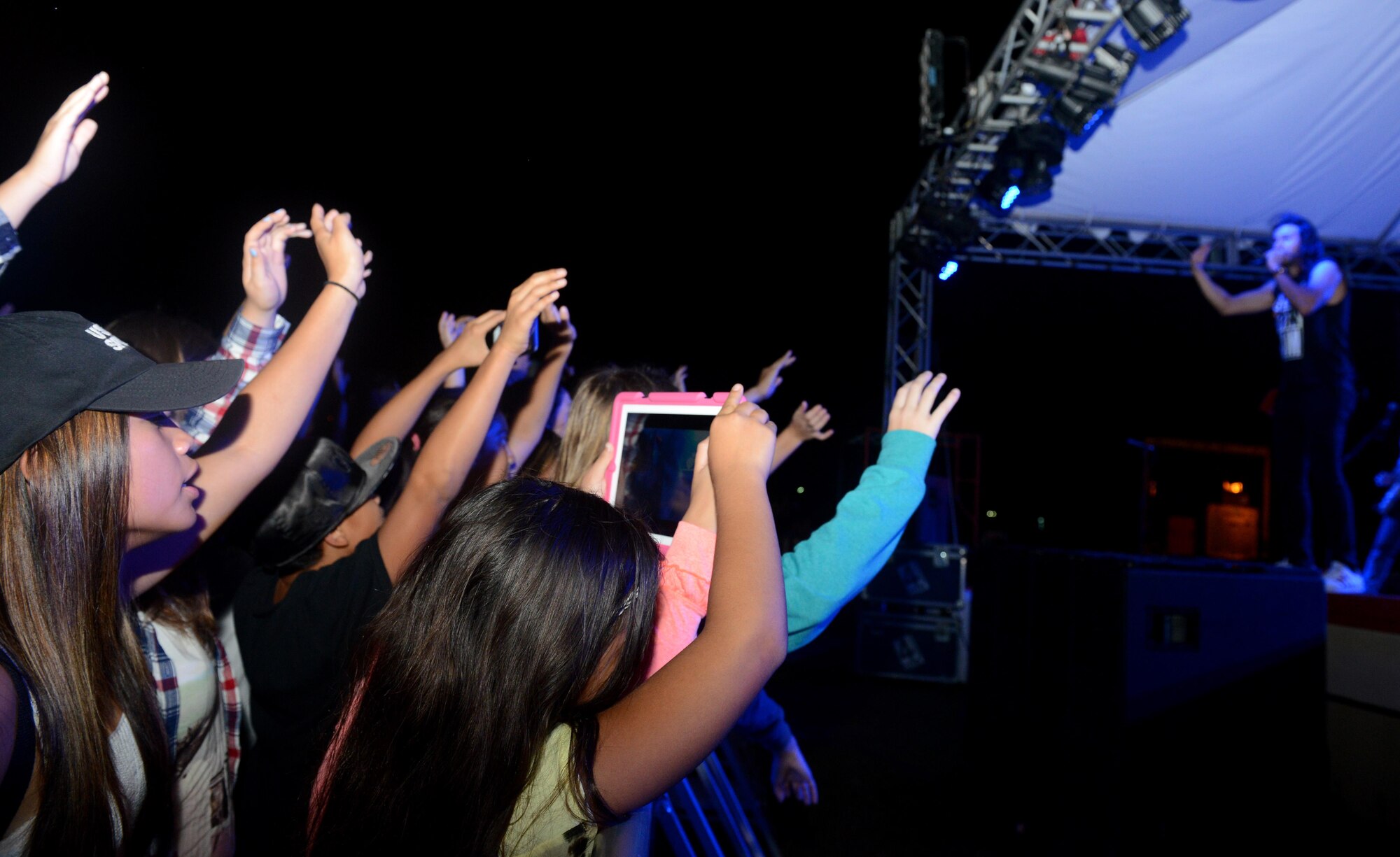 A crowd of service members and their families wave their arms as the Canadian reggae fusion band Magic! performs  a song Jan. 14, 2016, at Andersen Air Force Base, Guam. The band is well known for their debut single ‘Rude.’ (U.S. Air Force photo/Airman 1st Class Arielle Vasquez)