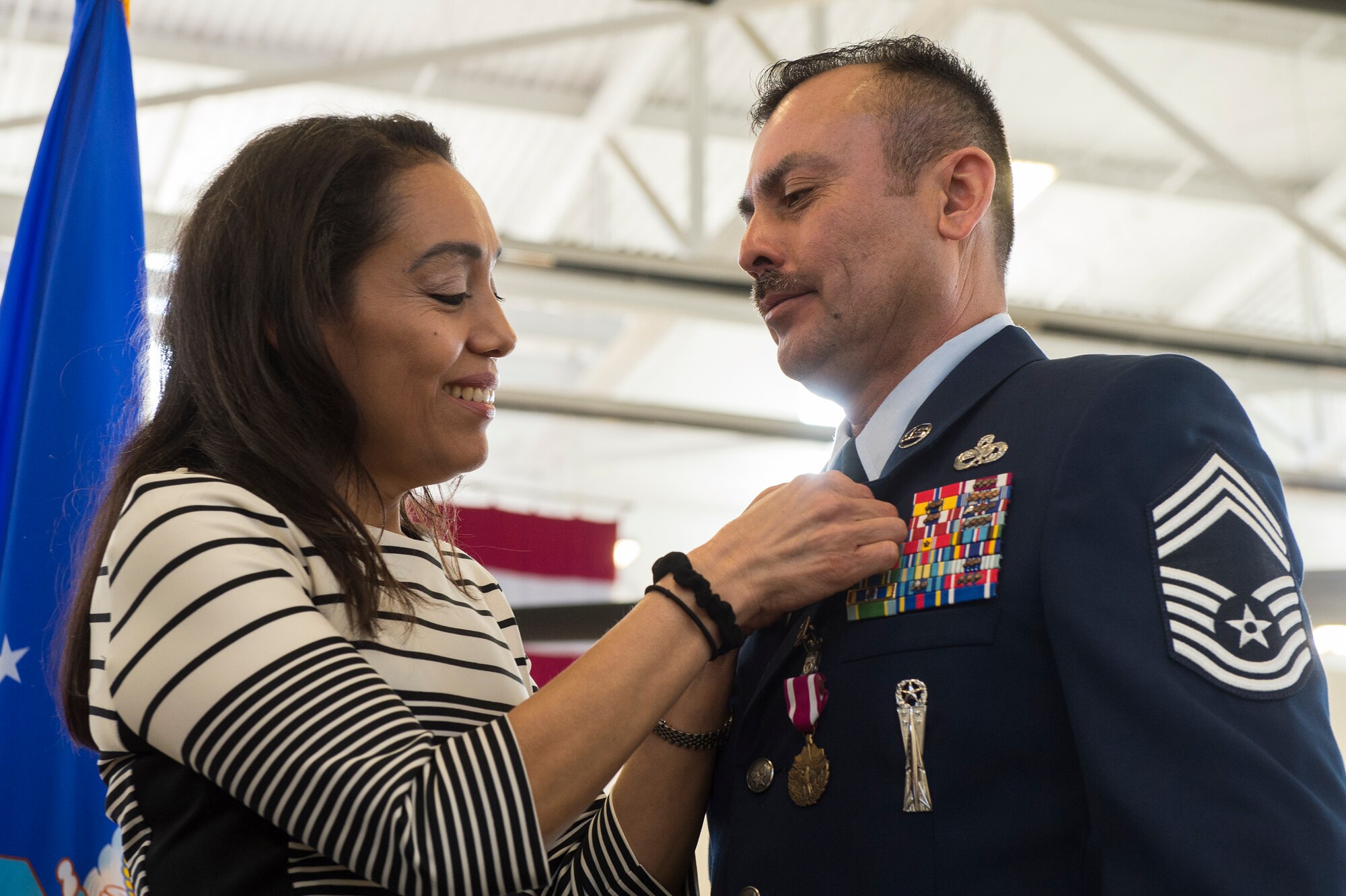 Beatriz Castillo, wife of Chief Master Sgt. Guillermo Castillo, 23d Maintenance Group wing weapons manager, clasps her husband’s retirement pin to his service jacket during Castillo’s retirement ceremony, Jan. 15, 2016, at Moody Air Force Base, Ga. Throughout his career, Castillo deployed to England, Kuwait, and Afghanistan in support of Operations DESERT STORM, SOUTHERN WATCH and ENDURING FREEDOM. (U.S. Air Force photo by Senior Airman Ceaira Tinsley/Released)