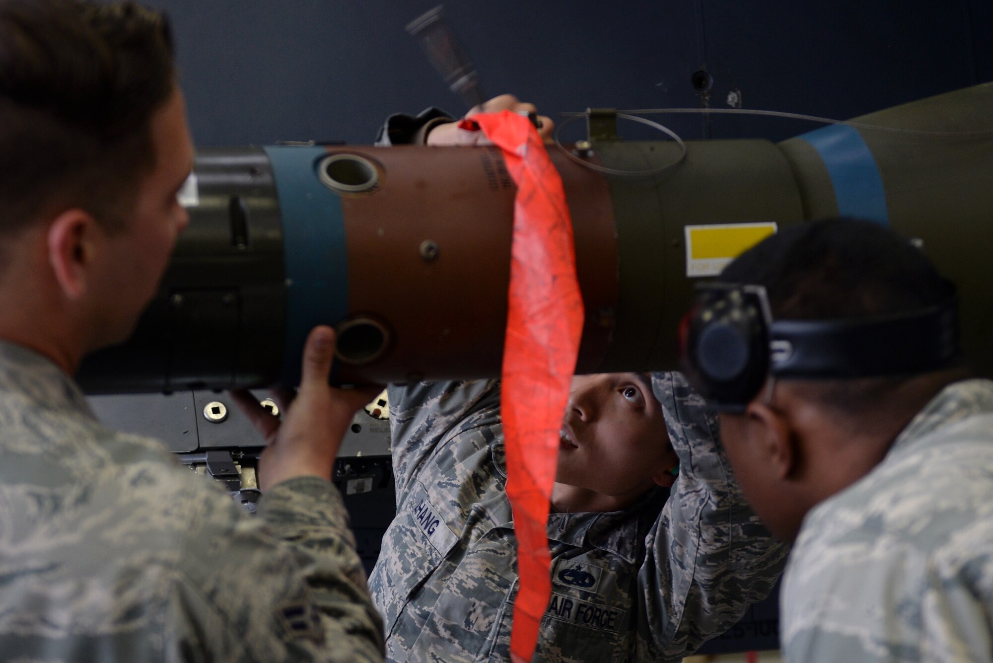 With the help of Airman 1st Class Thane Covert (left), and Senior Airman Jarrod Palileo (right), 4th Aircraft Maintenance Squadron weapons load crew members, Staff Sgt. Peige Zhang, 4th AMXS weapons load crew chief, attaches a munition to an F-15E Strike Eagle during the Load Crew of the Year competition, Jan. 15, 2016, at Seymour Johnson Air Force Base, North Carolina. The winners of the competition will be announced during the annual Maintenance Professional of the Year banquet in February. (U.S. Air Force photo/Senior Airman John Nieves Camacho)