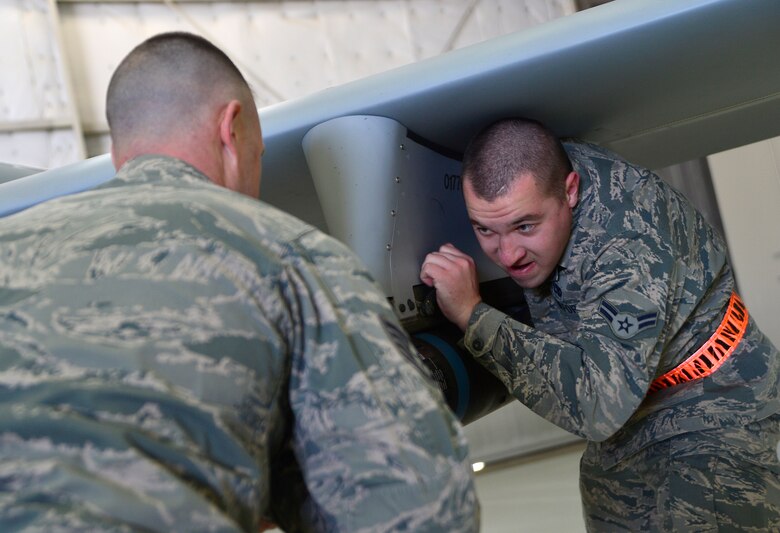 Staff Sgt. Justin, 432nd Aircraft Maintenance Squadron weapons load crew chief, left, and Airman 1st Class Stuart, 432nd AMXS weapons load crew member, load a Hellfire missile on an MQ-1 Predator aircraft during the fourth quarter Load Crew of the Quarter competition Jan. 14, 2016, at Creech Air Force Base, Nevada. The Load Crew of the Quarter competition challenges crews from two aircraft maintenance units in a friendly competition to improve camaraderie, morale, and readiness.  (U.S. Air Force photo by Senior Airman Christian Clausen/Released)