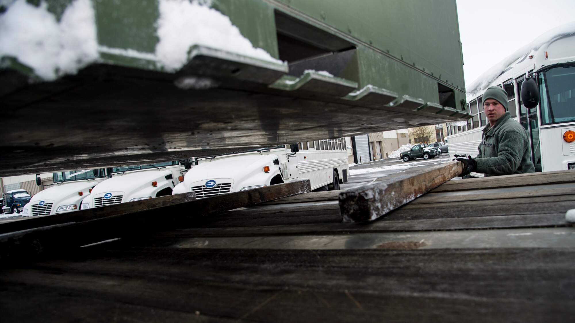 Airman 1st Class Auston R. Reeves, 92nd Logistics Readiness Squadron vehicle operations journeyman, slides pieces of wood under a container before placing it on the flatbed trailer Jan. 10, 2015, at Fairchild Air Force Base, Wash. For each job vehicle ops conducts, they use a specific vehicle. For transporting cad bins and other equipment, they have tractor trailer trucks with several different styles of trailers for towing. (U.S. Air Force photo/Airman 1st Class Sean Campbell)