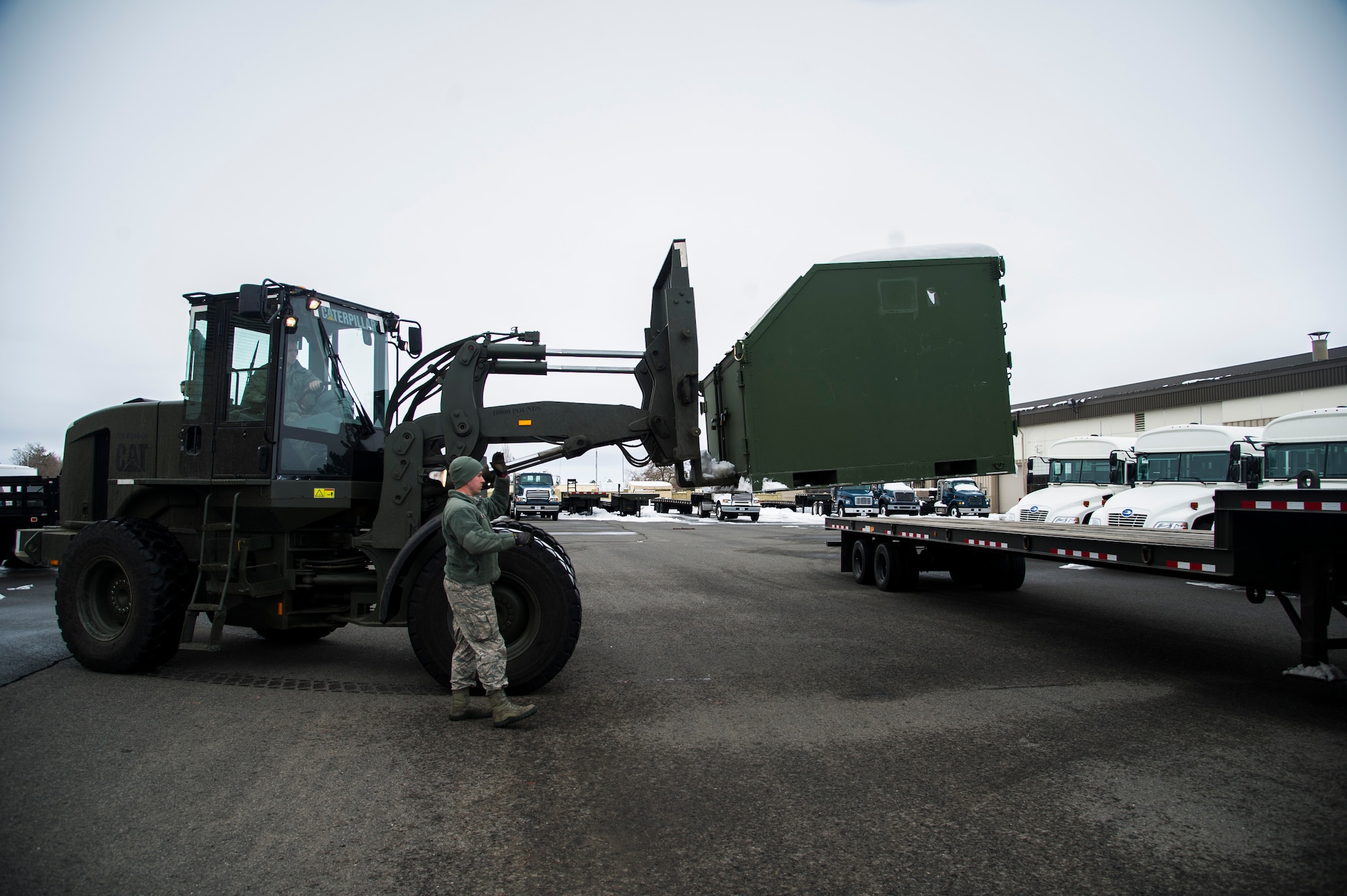 Airman 1st Class Auston R. Reeves, 92nd Logistics Readiness Squadron vehicle operations journeyman, guides Airman Tucker Gerdes 92nd LRS, vehicle operations journeyman, as he places a container on a flatbed trailer Jan. 10, 2015, at Fairchild Air Force Base, Wash. Vehicle ops moves a variety of different cargos ranging from personal gear to aircraft parts. (U.S. Air Force photo/Airman 1st Class Sean Campbell)