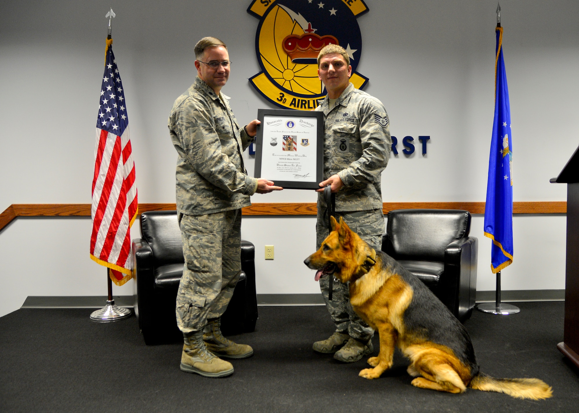 Lt. Col. Michael Phillips, 436th Mission Support Group deputy commander, presents Staff Sgt.  Jason Spangenberg, 436th Security Forces Squadron military working dog trainer, with MWD Rico/M137’s retirement certificate at Rico’s retirement ceremony Jan. 15, 2016, at Dover Air Force Base, Del. Spangenberg was assigned Rico for three years and is adopting him following Rico’s retirement. (U.S. Air Force photo/Senior Airman William Johnson)