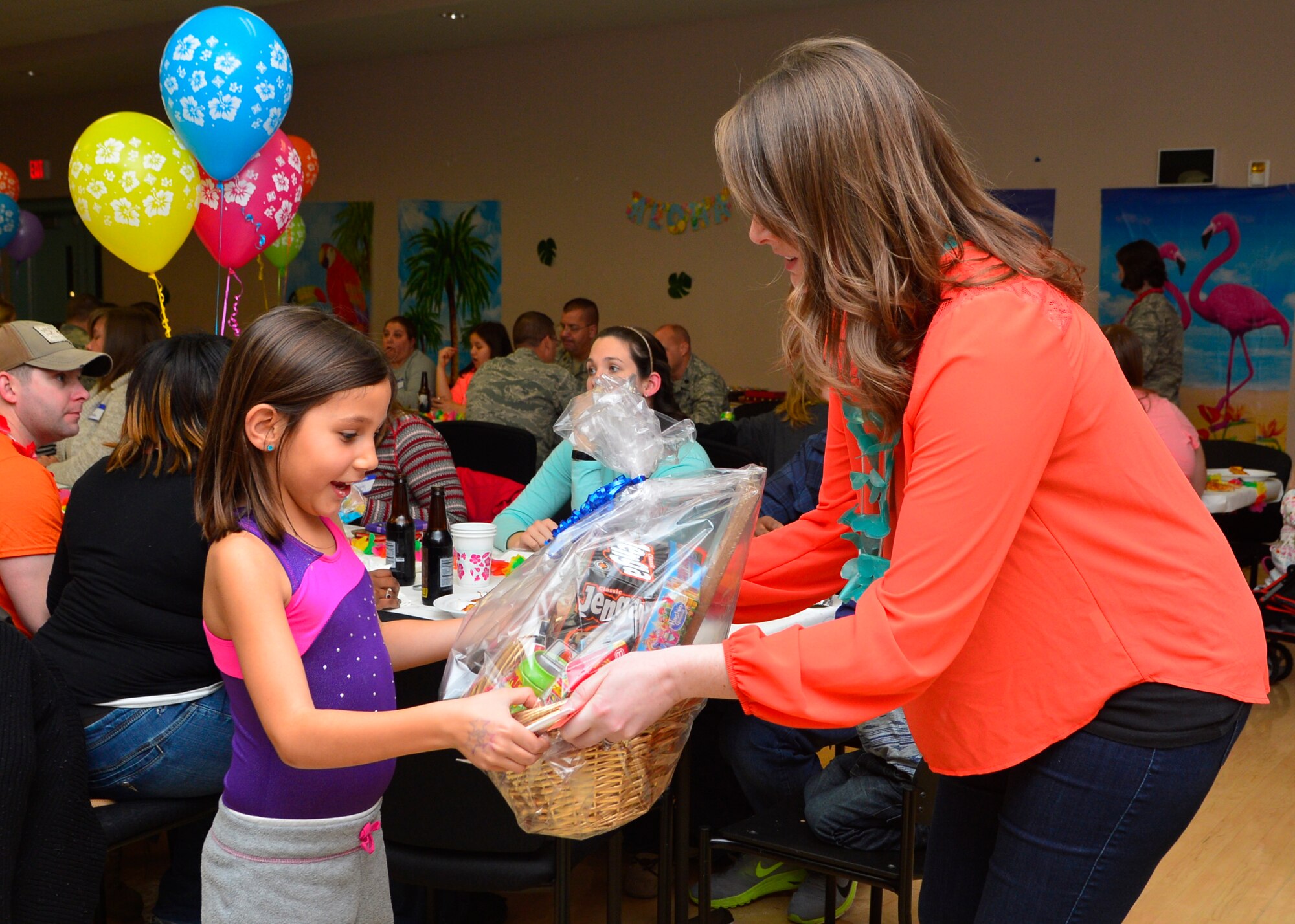 Sarah Smith hands Bella Garcia, daughter of Maj. Glenn Garcia, 3d Airlift Squadron pilot, a gift basket during a Deployed Families and Spouses Dinner Jan. 14, 2016, at the Youth Center on Dover Air Force Base, Del. A raffle was held at the dinner giving families of deployed members prizes and gift cards to local business and restaurants. (U.S. Air Force photo/Senior Airman William Johnson)