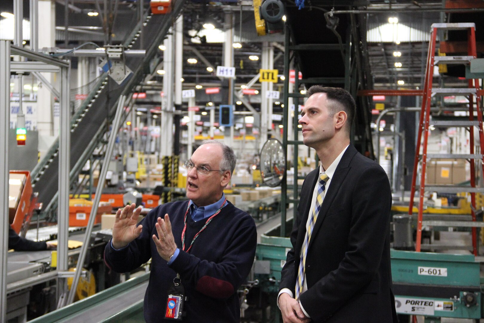 Major Ben Yanovich, Israeli Air Force, right, discusses DLA Distribution Susquehanna, Pa.’s, small parcel area with Ron Hunziker, a subject matter expert at the distribution center.