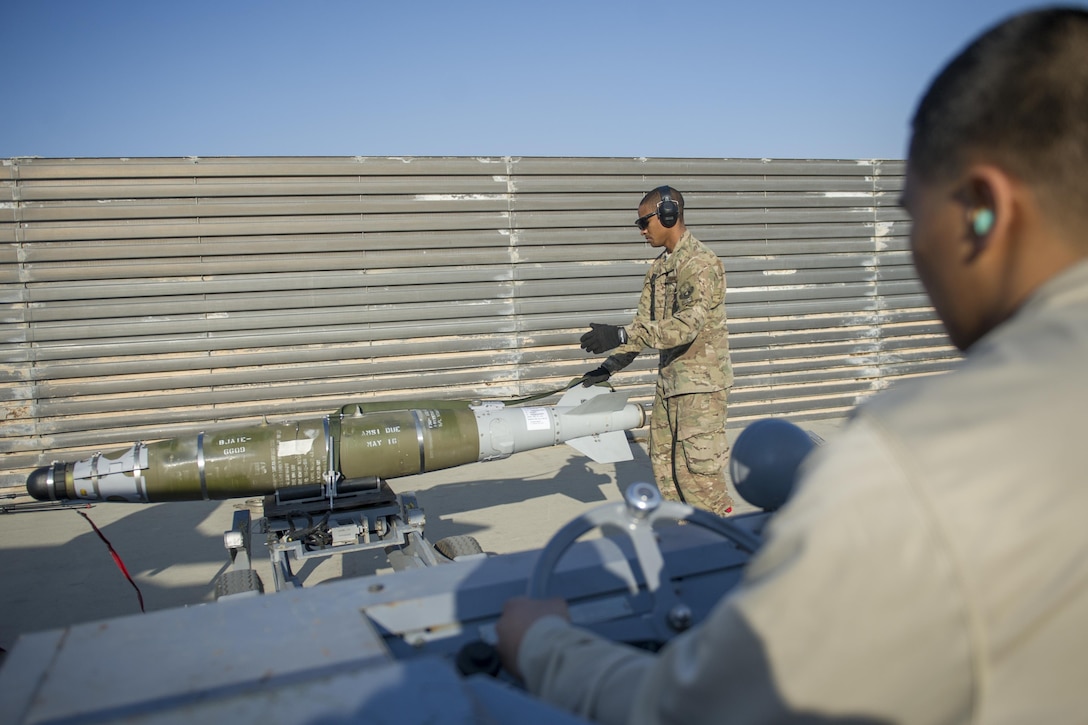 Air Force Staff Sgt. Chris White, background, guides a GBU-54 to a jammer driven by Airman 1st Class Rhaymark Neri during a 30-day inspection on Bagram Airfield, Afghanistan, Jan. 15, 2016. U.S. Air Force photo by Tech. Sgt. Robert Cloys